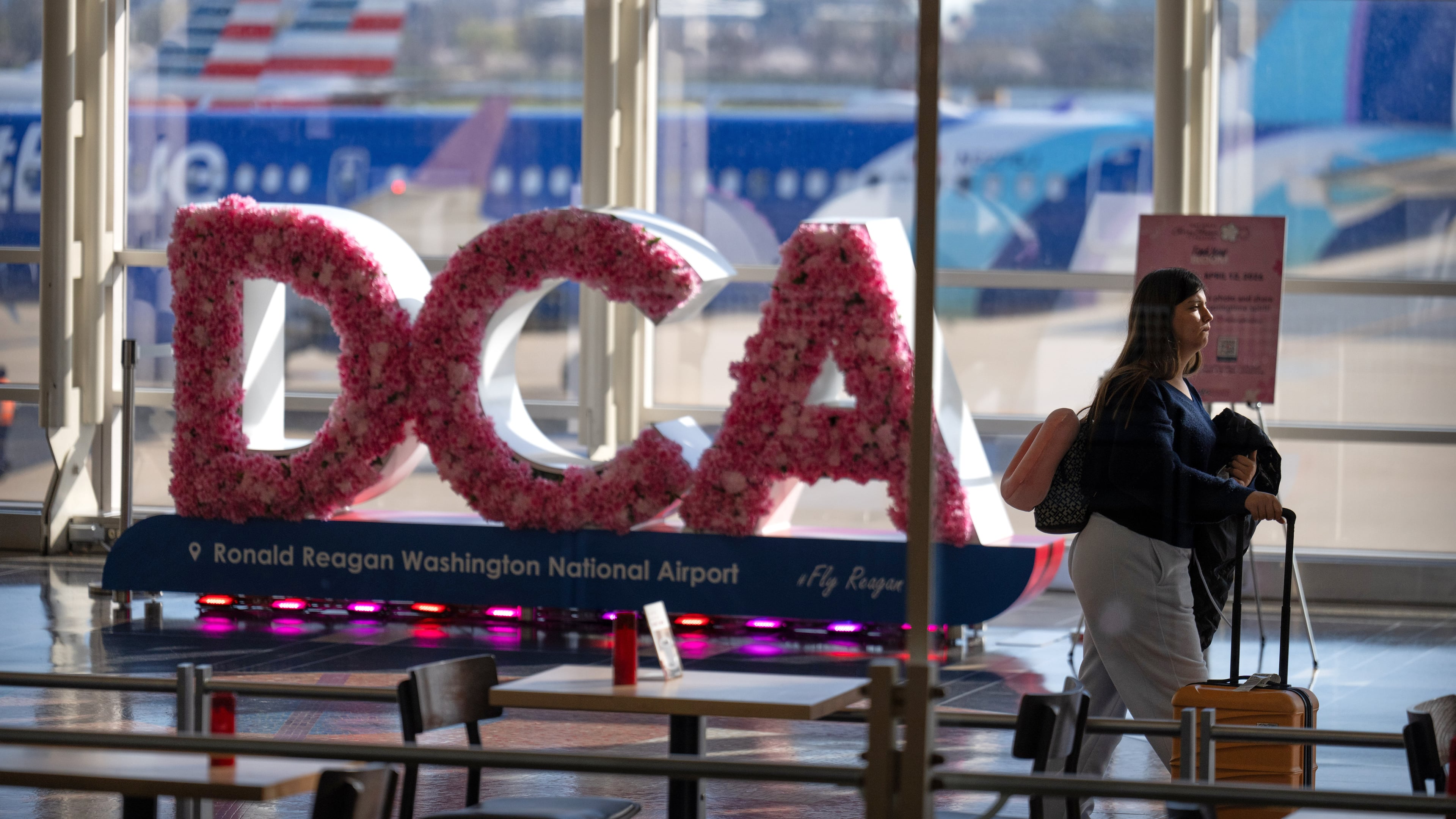A traveler walks along the concourse at Reagan National Airport, Tuesday, March 24, 2026, in Washington. (AP Photo/Mark Schiefelbein)