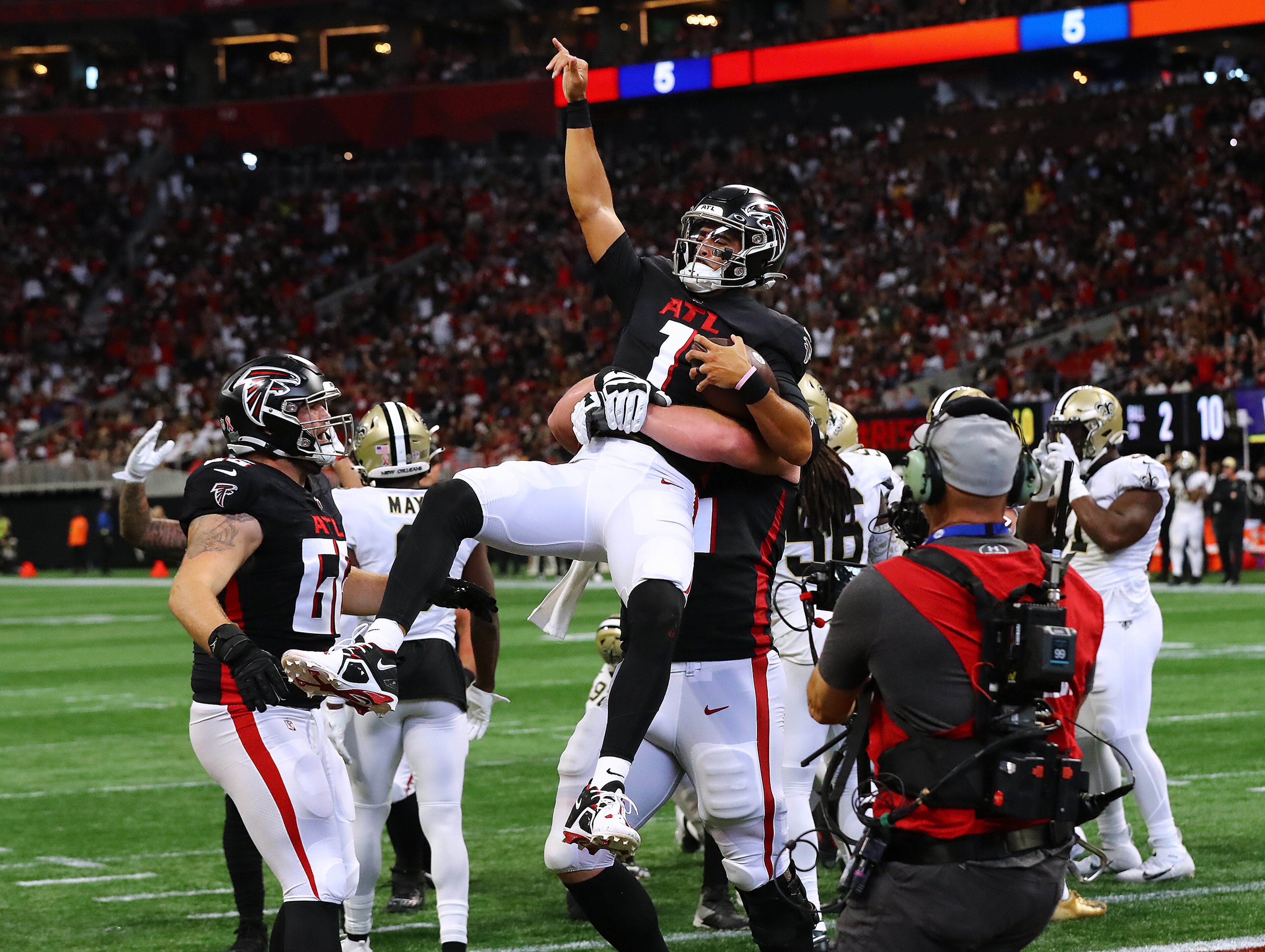 Falcons quarterback Marcus Mariota and tackle Kaleb McGary celebrate after Mariota scored during the third quarter Sunday. (Curtis Compton / Curtis Compton@ajc.com)