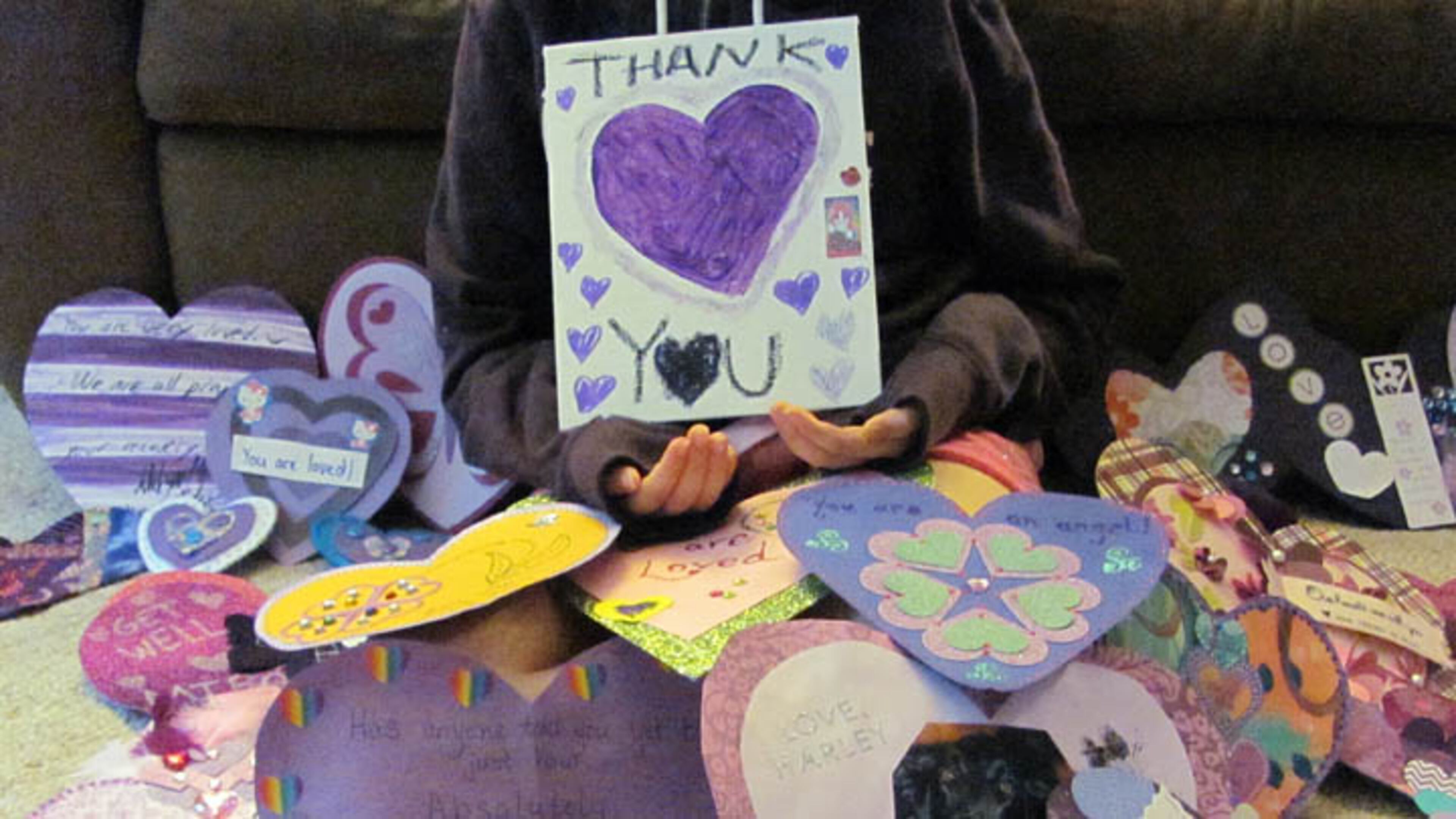 In this June 19, 2014 photo provided by Dana Hoffmann, a 12-year-old Waukesha, Wisconsin girl who wished to remain unidentified, holds a "Thank You" poster for the many supporters from around the world that have sent her cards. The girl, stabbed 19 times in the legs, arms and torso last month, is making steady physical and emotional progress, but her movement is limited by breathing problems, her family said. Court documents indicate that two 12-year-old classmates stabbed the girl in a plan to curry favor with Slender Man, a character in horror stories they had read online. (AP Photo/Dana Hoffmann)