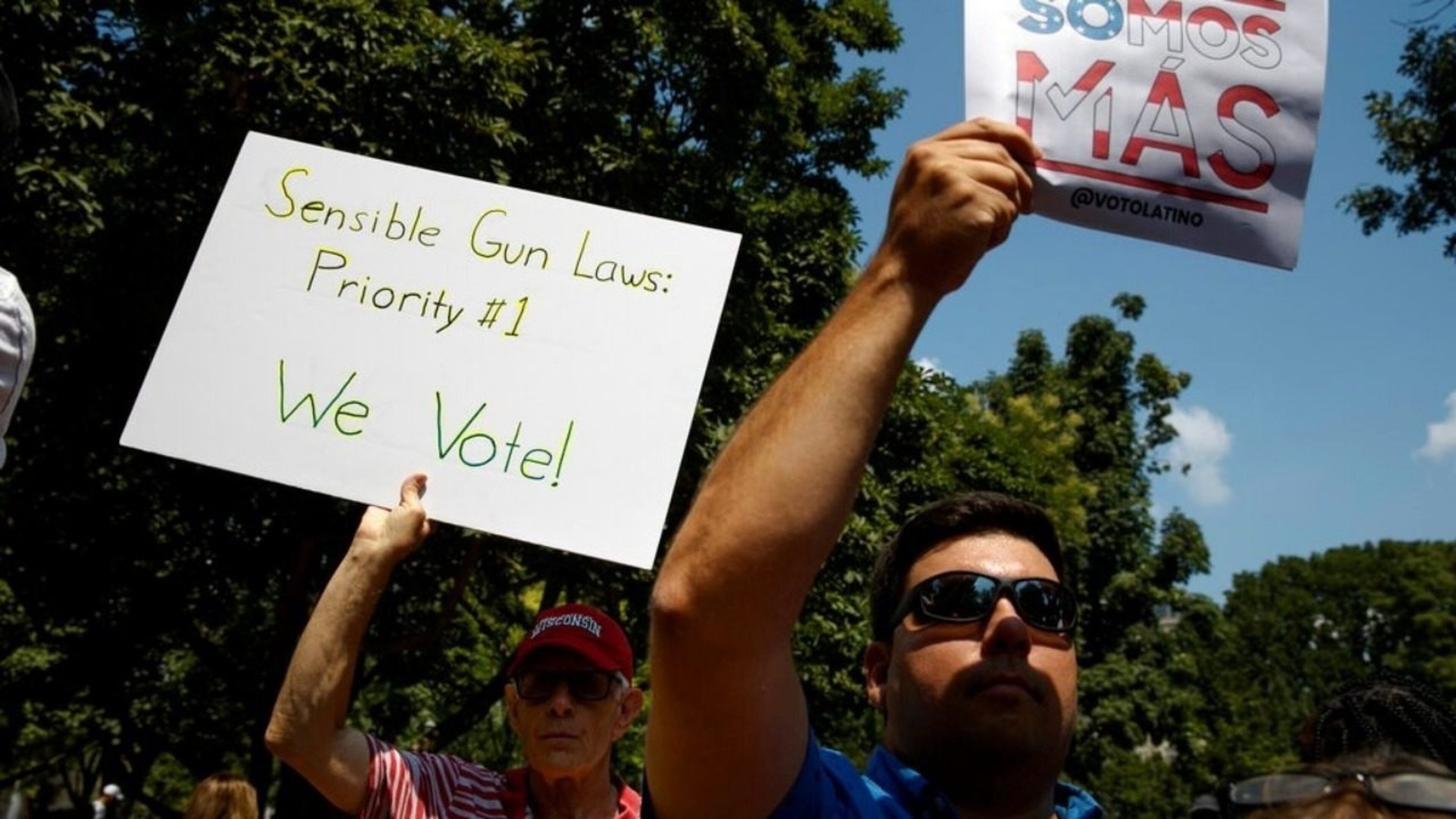 Men hold up signs during a rally against racism and white nationalism and in favor of gun laws, Tuesday, Aug. 6, 2019, near the White House in Washington.
