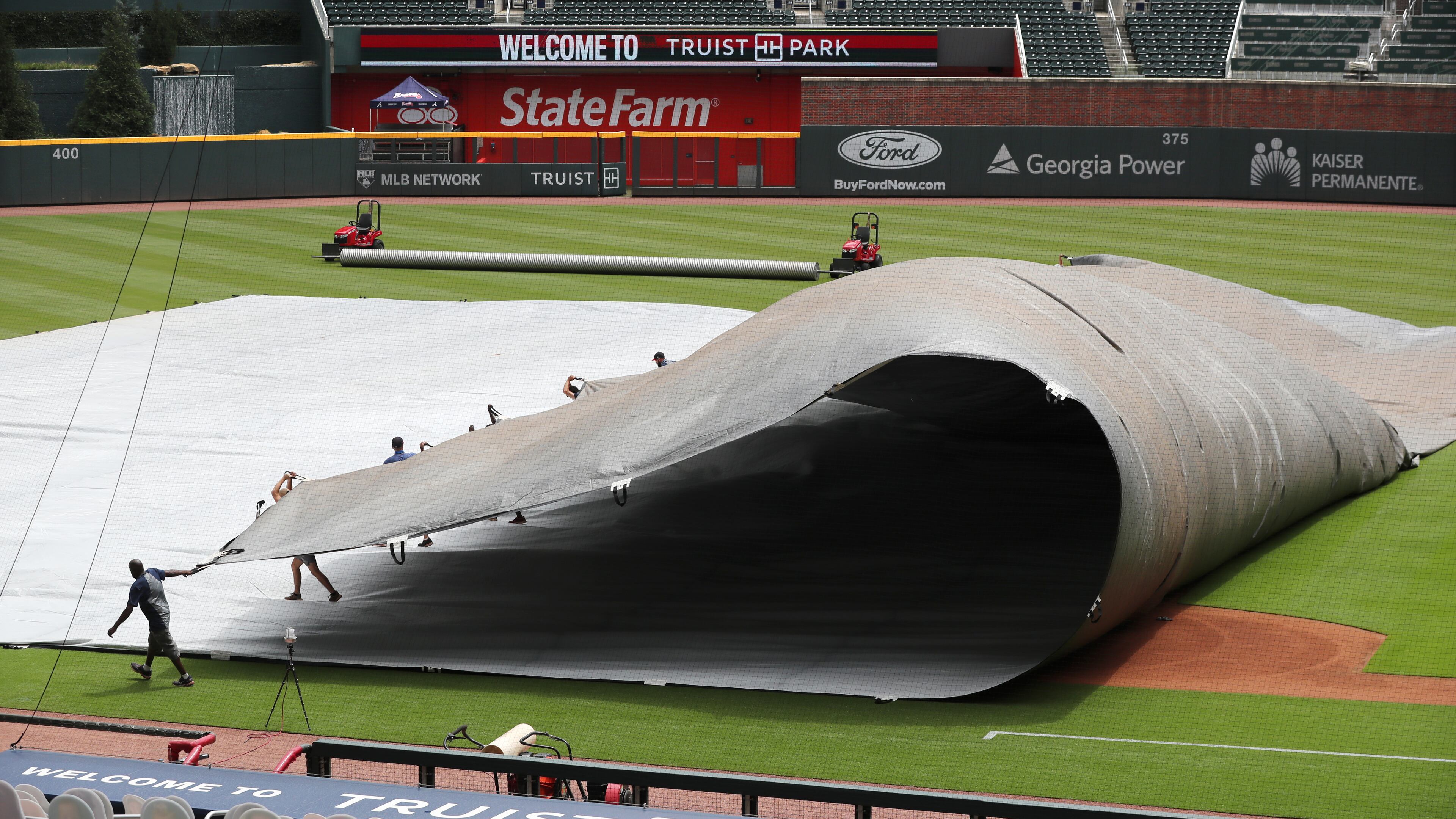 The Braves ground crew removes the giant field tarp prior to Wednesday's home opener against the Tampa Bay Rays. (Curtis Compton/ccompton@ajc.com)