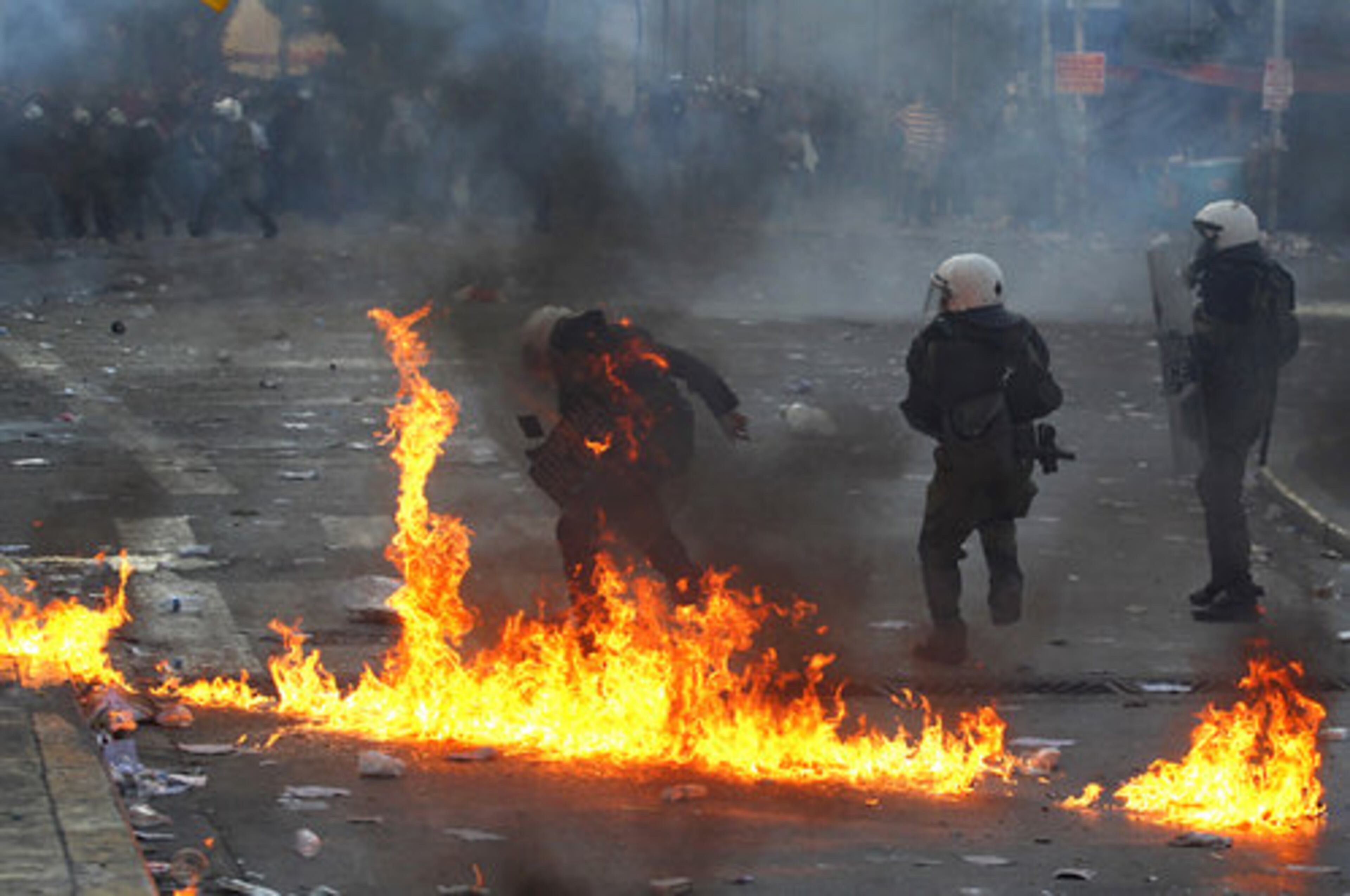 A riot policeman's clothing catches fire after being hit by a Molotov cocktail.