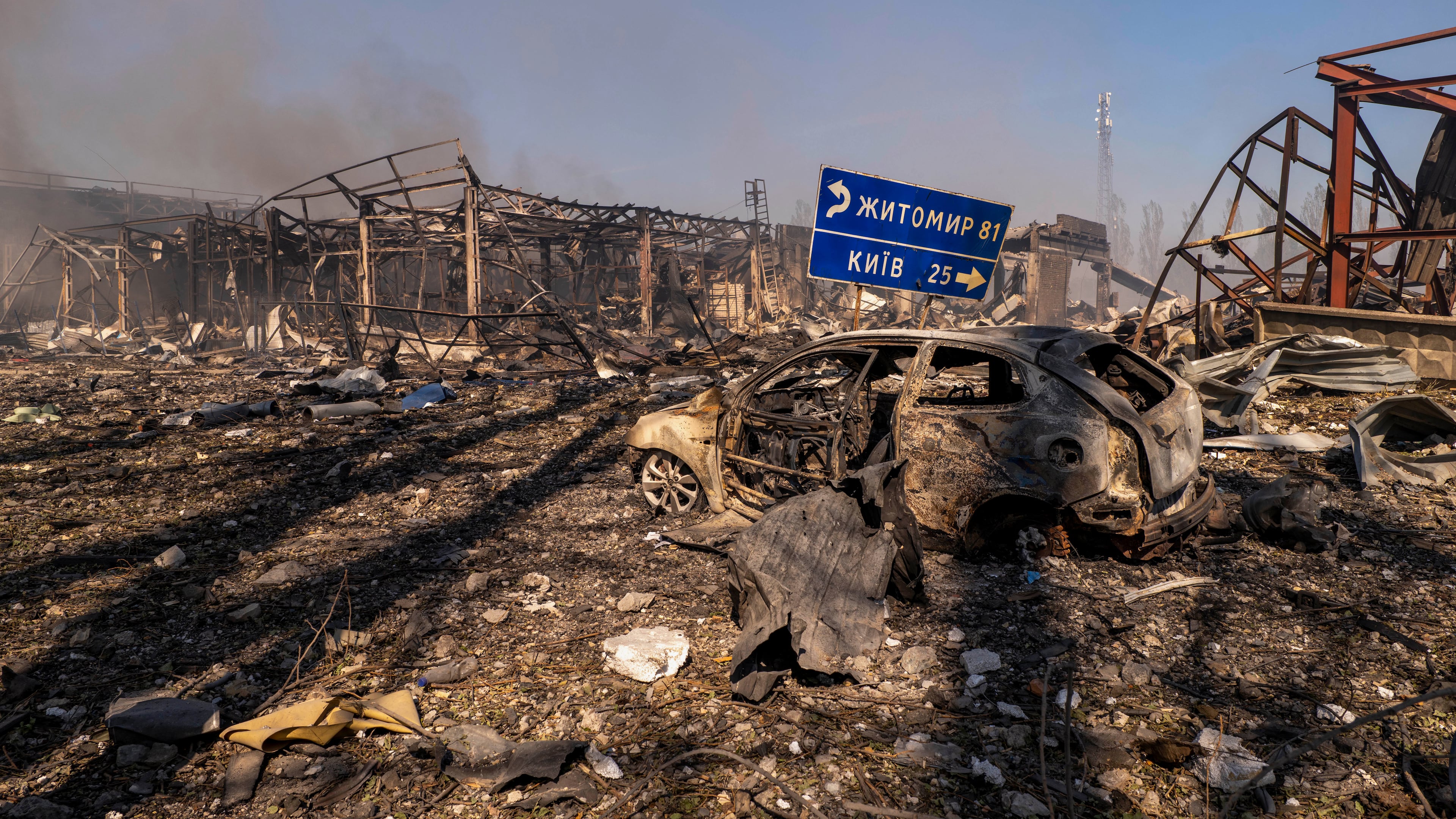 A view of a destroyed car amid damaged buildings, with a road sign showing the direction and distance to Kyiv and Zhytomyr after a Russian attack struck a warehouse, followed by an explosion, in the village of Myla, Kyiv region, Ukraine, Saturday, Aug. 29, 2026. (AP Photo/Dan Bashakov)