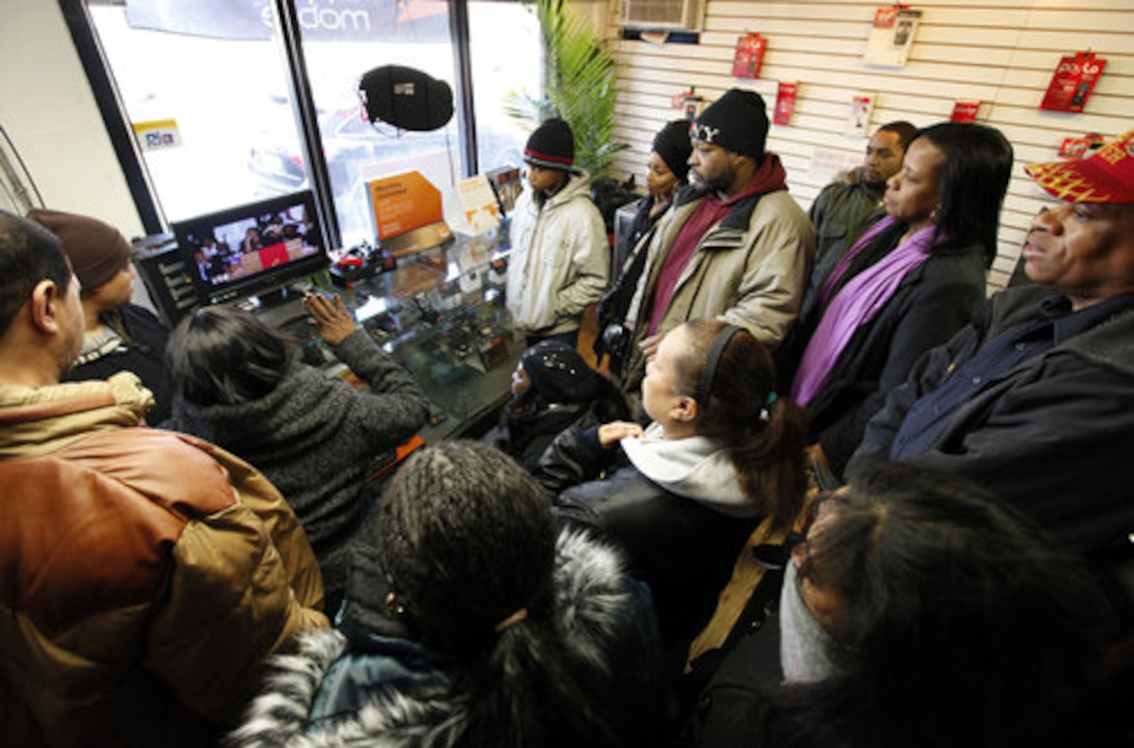 Whitney Houston fans gather around a television in a mobile phone store a few blocks from the New Hope Baptist Church to watch the singer's funeral in Newark, N.J., Saturday, Feb. 18, 2012.