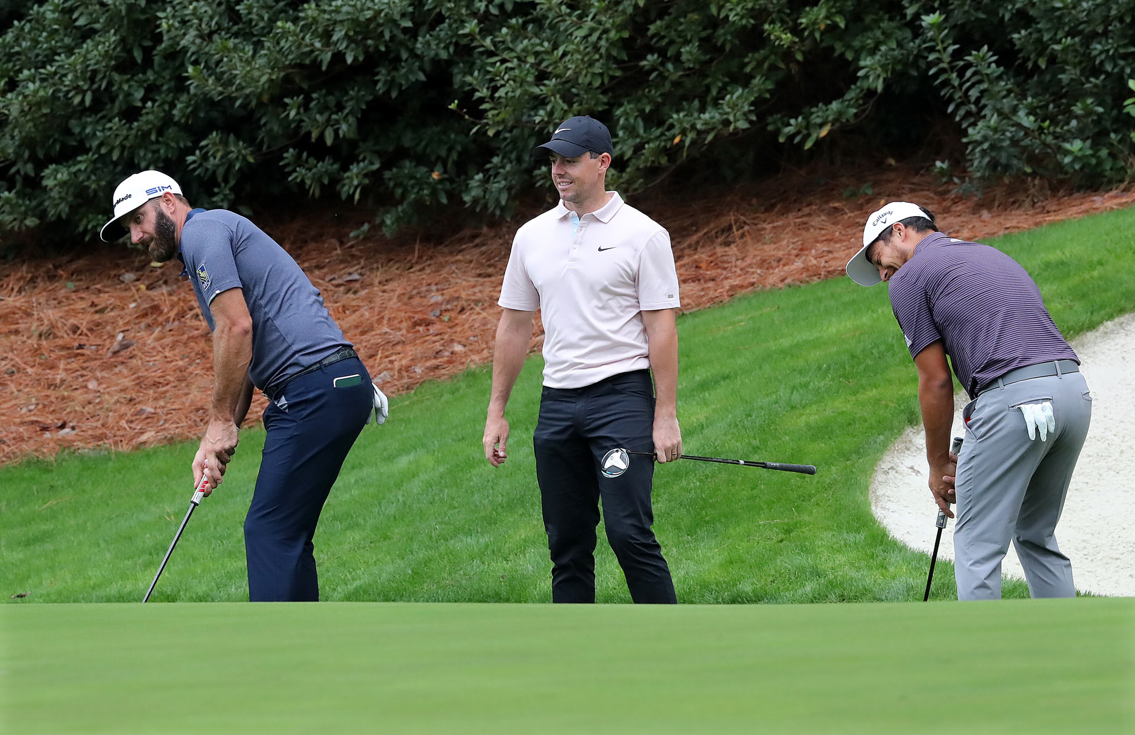 Dustin Johnson (left), Rory McIIroy (middle), and Xander Schauffele practice their putting at the 13th green. “Curtis Compton / Curtis.Compton@ajc.com”