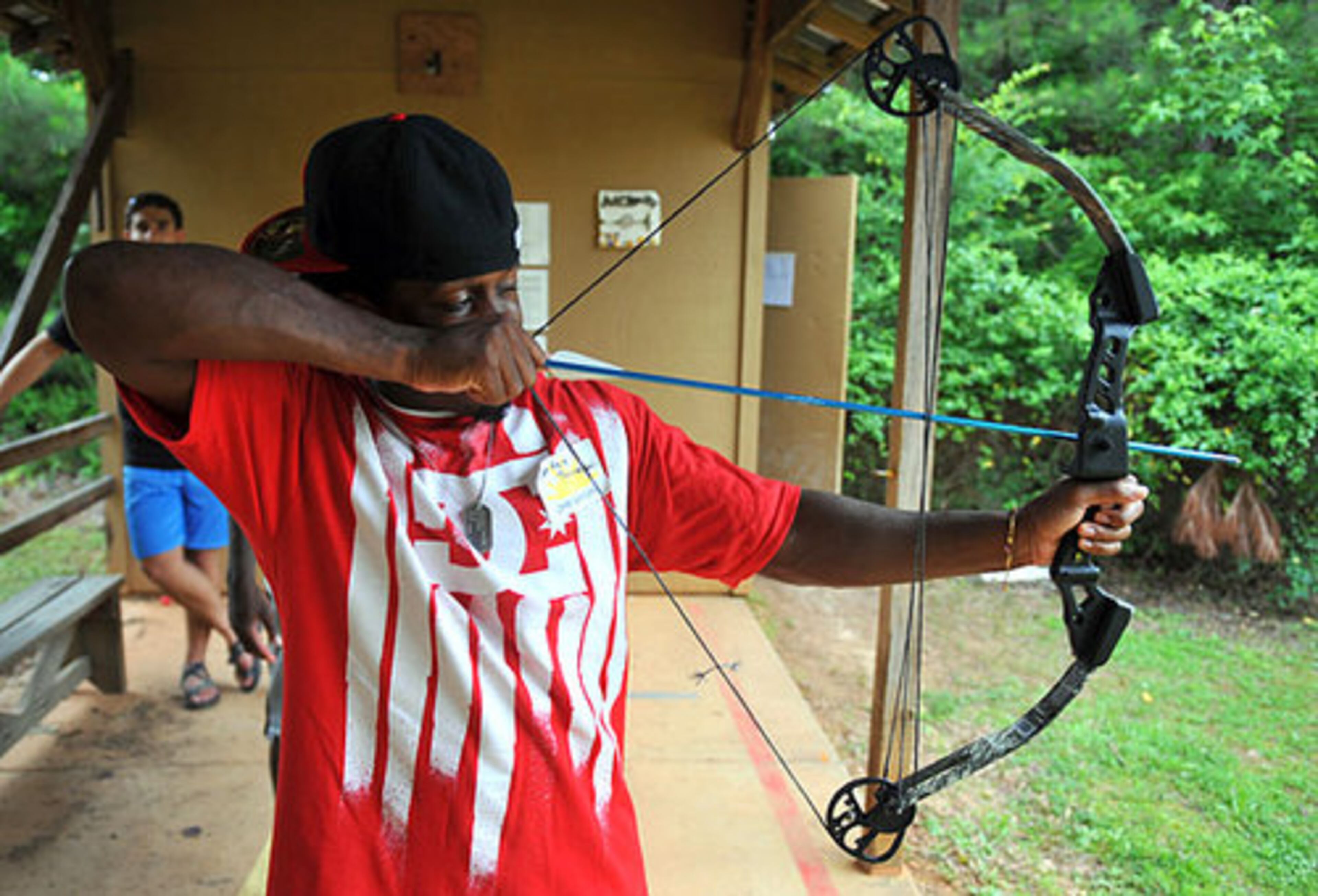 UGA running back Carlton Thomas tries his hand at archery while visiting with kids at Camp Sunshine.