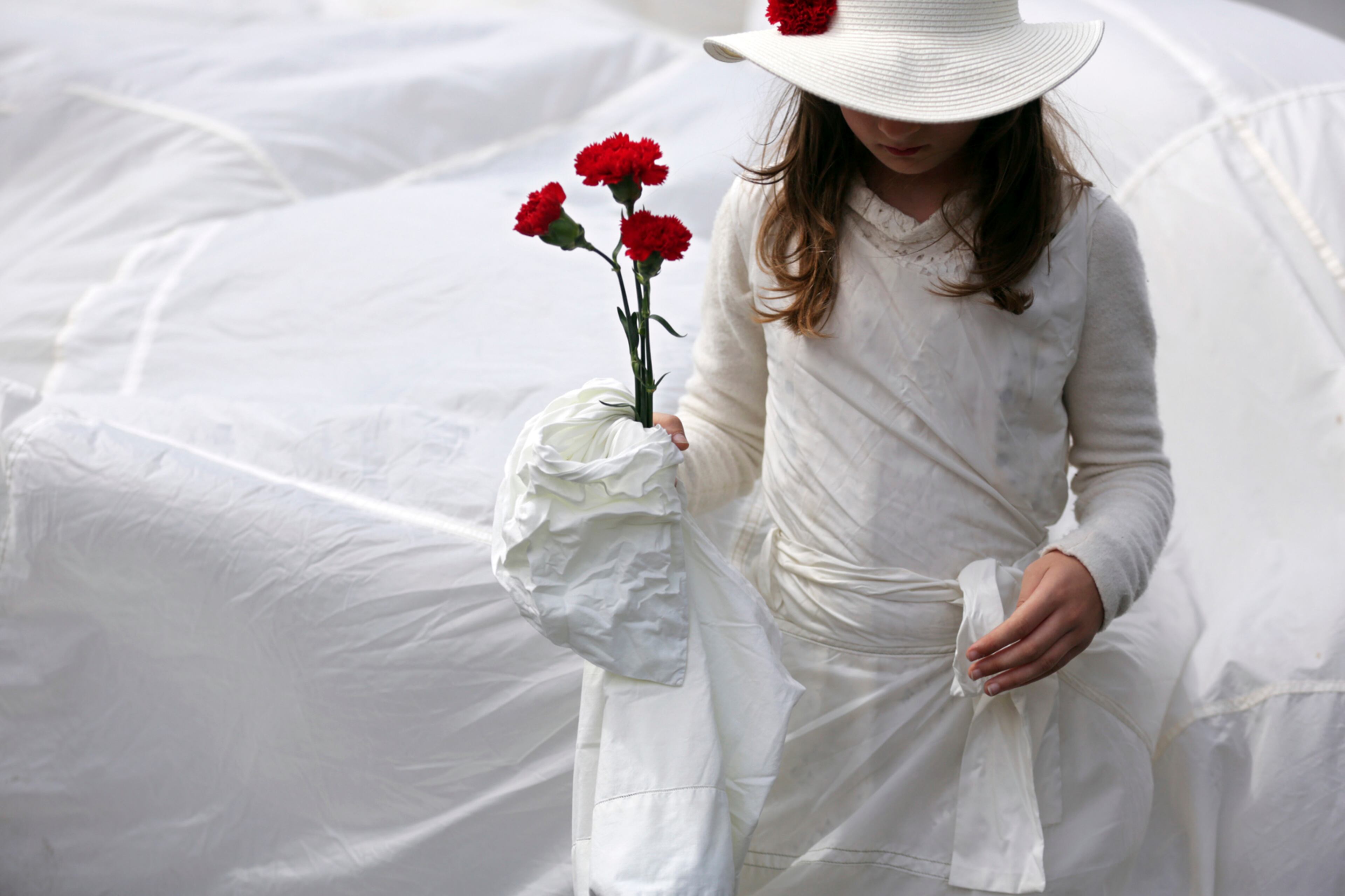 A girl from a group of performers carries red carnations while taking part in a parade celebrating the April 25 1974 revolution, also known as the Revolution of the Carnations, Tuesday, April 25 2017. The red carnation is the symbol of the 1974 revolution that restored democracy in Portugal after nearly half century of fascist dictatorship. (AP Photo/Armando Franca)