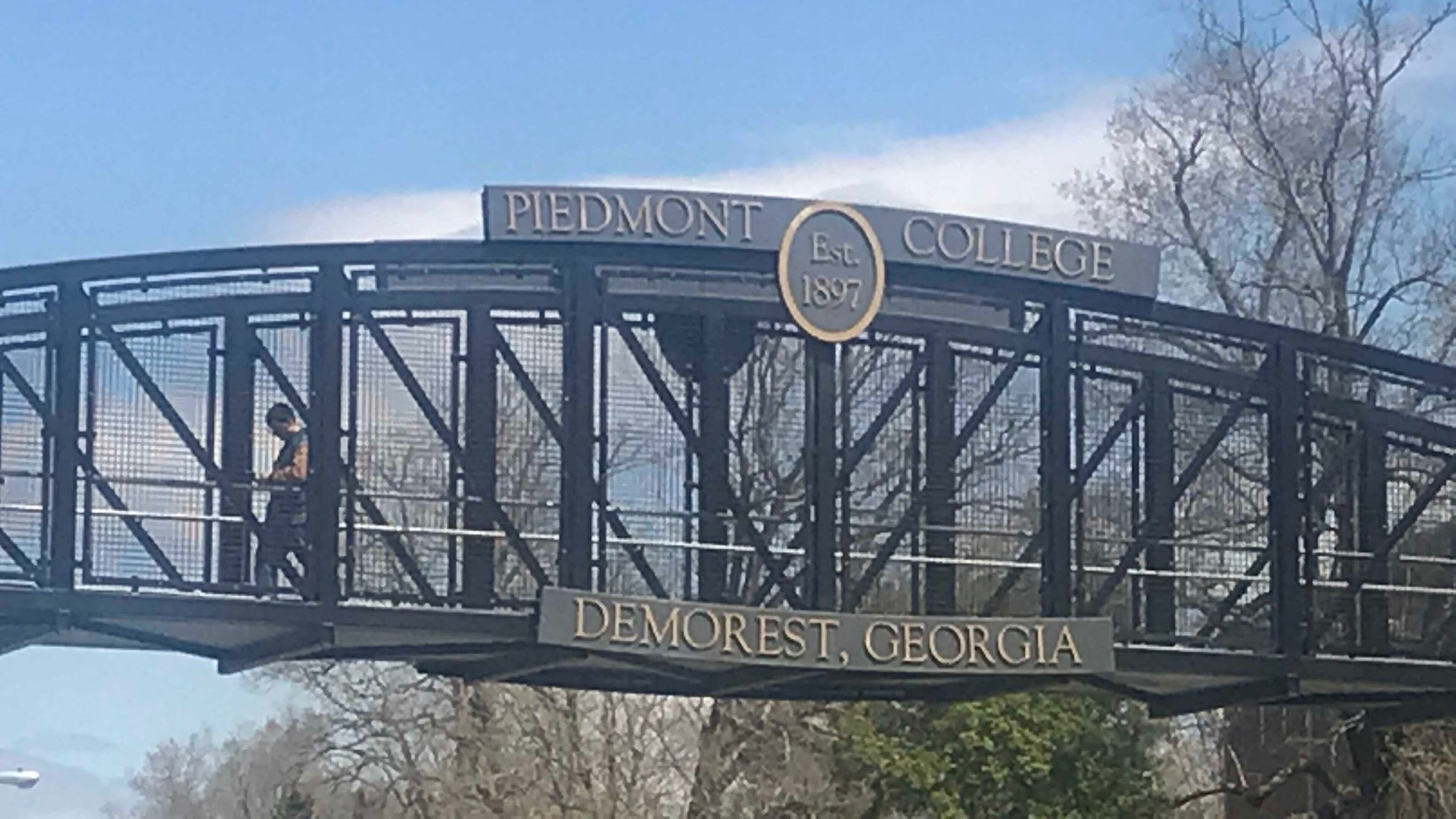 A man walks across the bridge connecting portions of Piedmont College’s main campus in Habersham County. ERIC STIRGUS / ESTIRGUS@AJC.COM