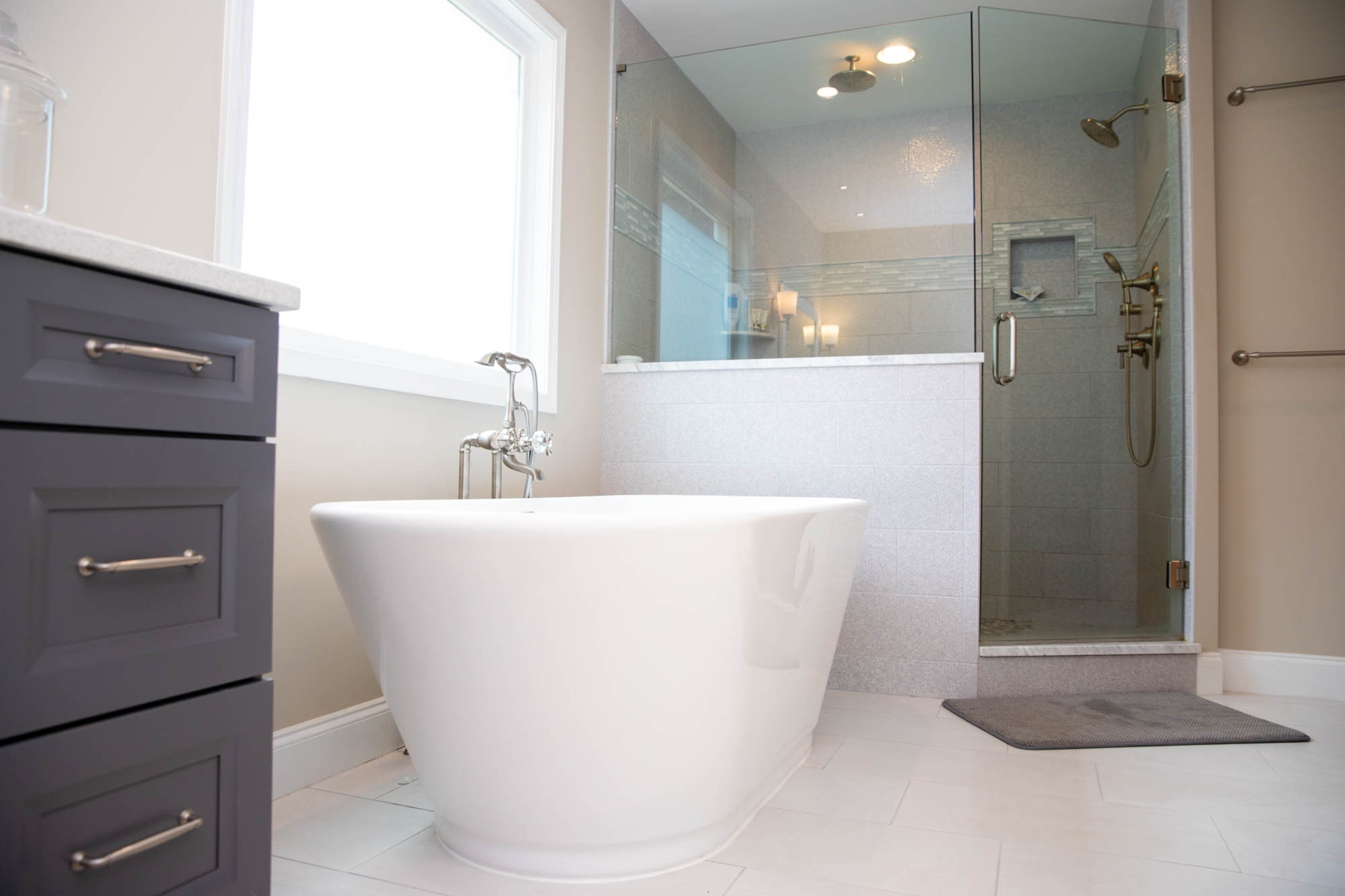 A large shower with Maya Perla tile accented by a strip in Key Largo glass mosaic and trimmed in a Carrara marble pencil tile all from The Tile Shop along with double shower heads from Moen completes the spa-like master bathroom in Seth and Allie Ott's DeKalb County home.