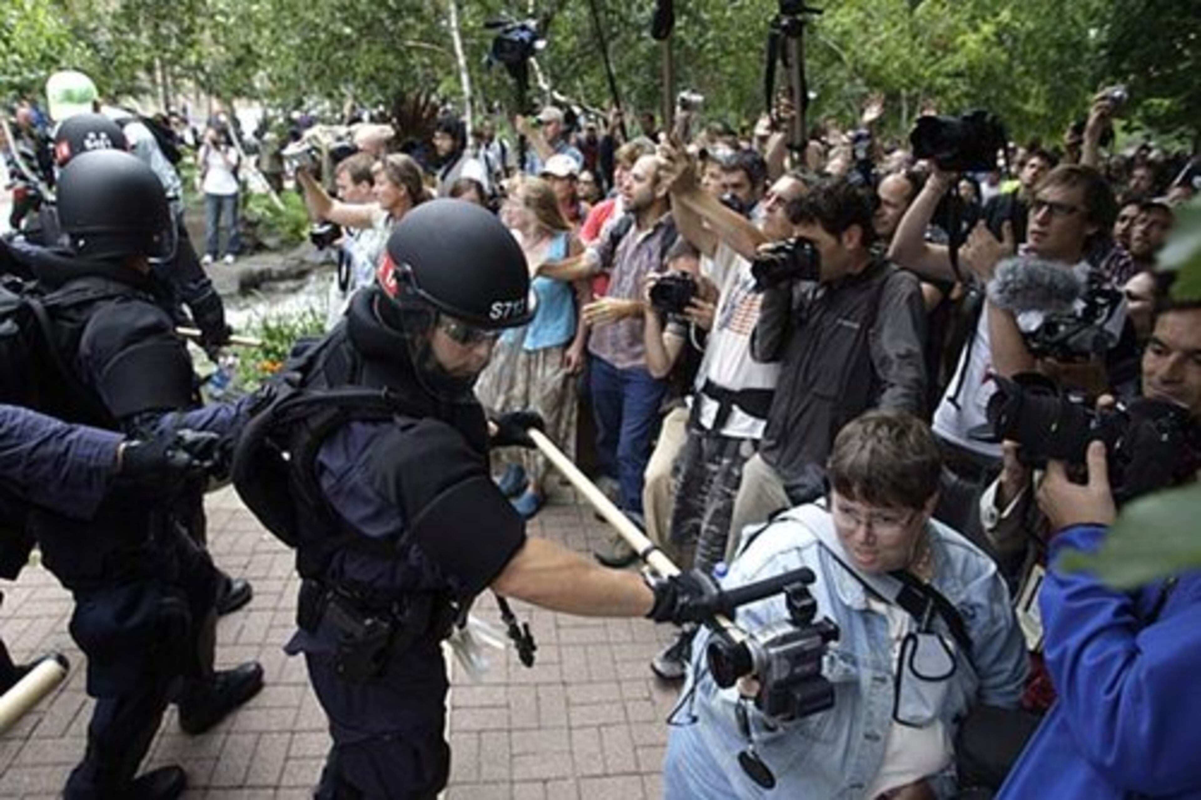 Police officers hold back a crowd during a protest Tuesday at the Republican National Convention. The officer in the foreground is filming the protesters with a videocamera mounted on a pole.