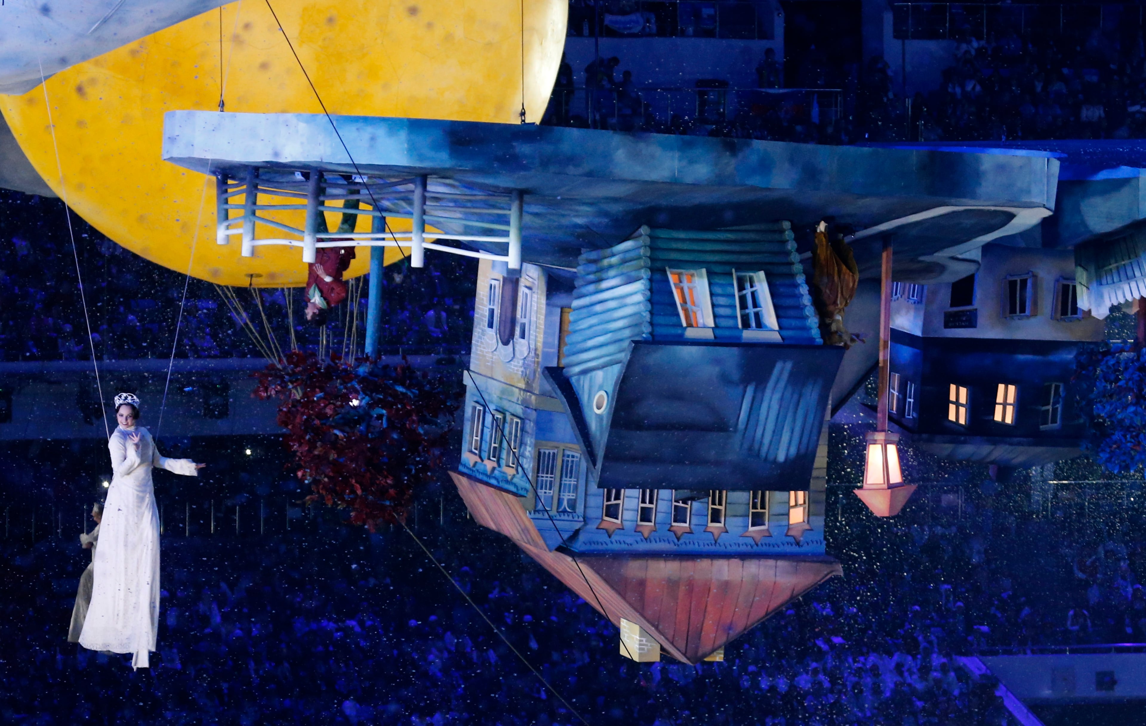 An artist is suspended near an upside-down house as part of a performance during the closing ceremony of the 2014 Winter Olympics, Sunday, Feb. 23, 2014, in Sochi, Russia. (AP Photo/Dmitry Lovetsky)