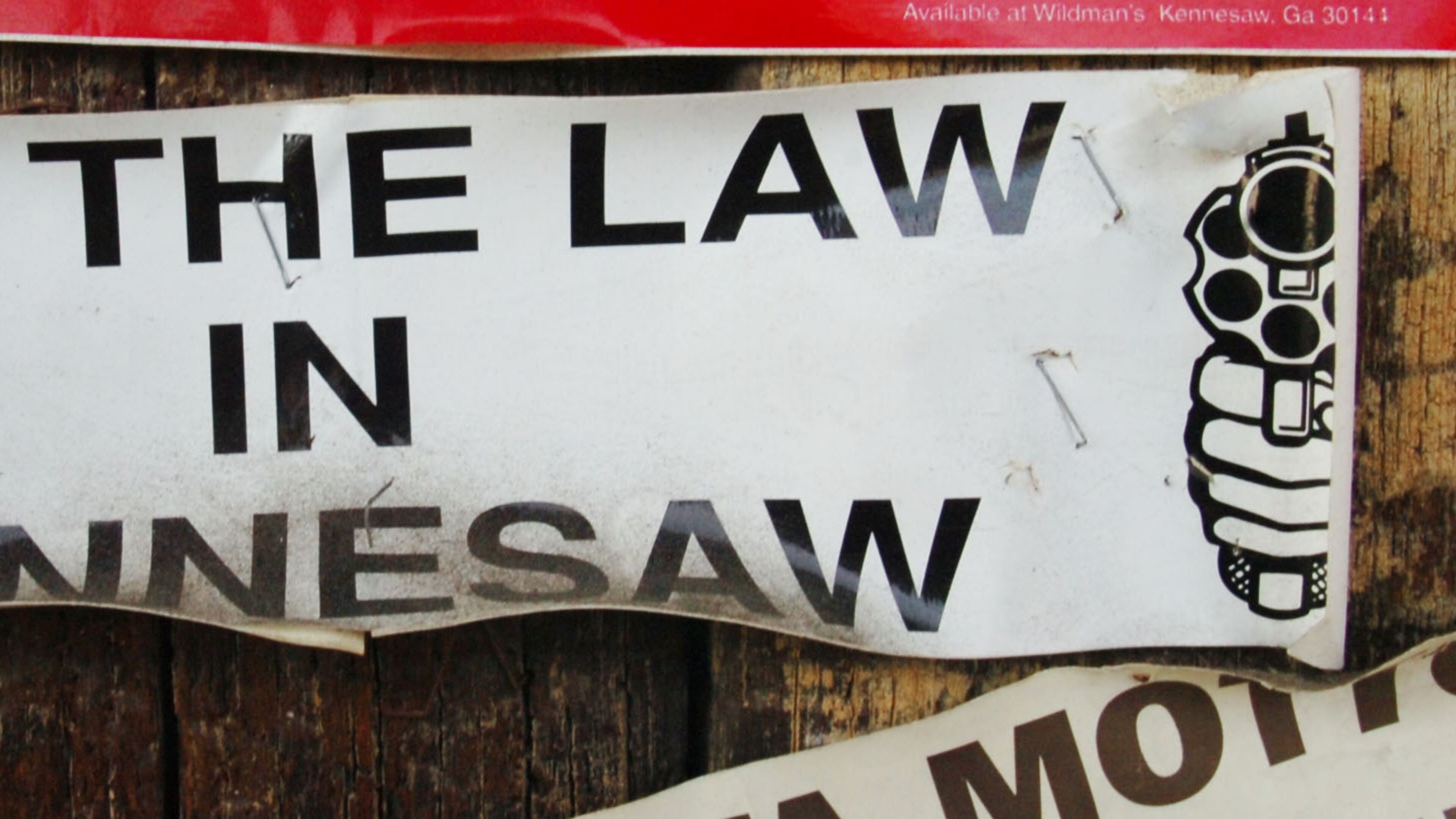 In this 2007 photo, we see a weathered old bumper sticker that refers to the Kennesaw ordinance that requires heads of households to own a firearm – unless they don’t want to. AJC file.