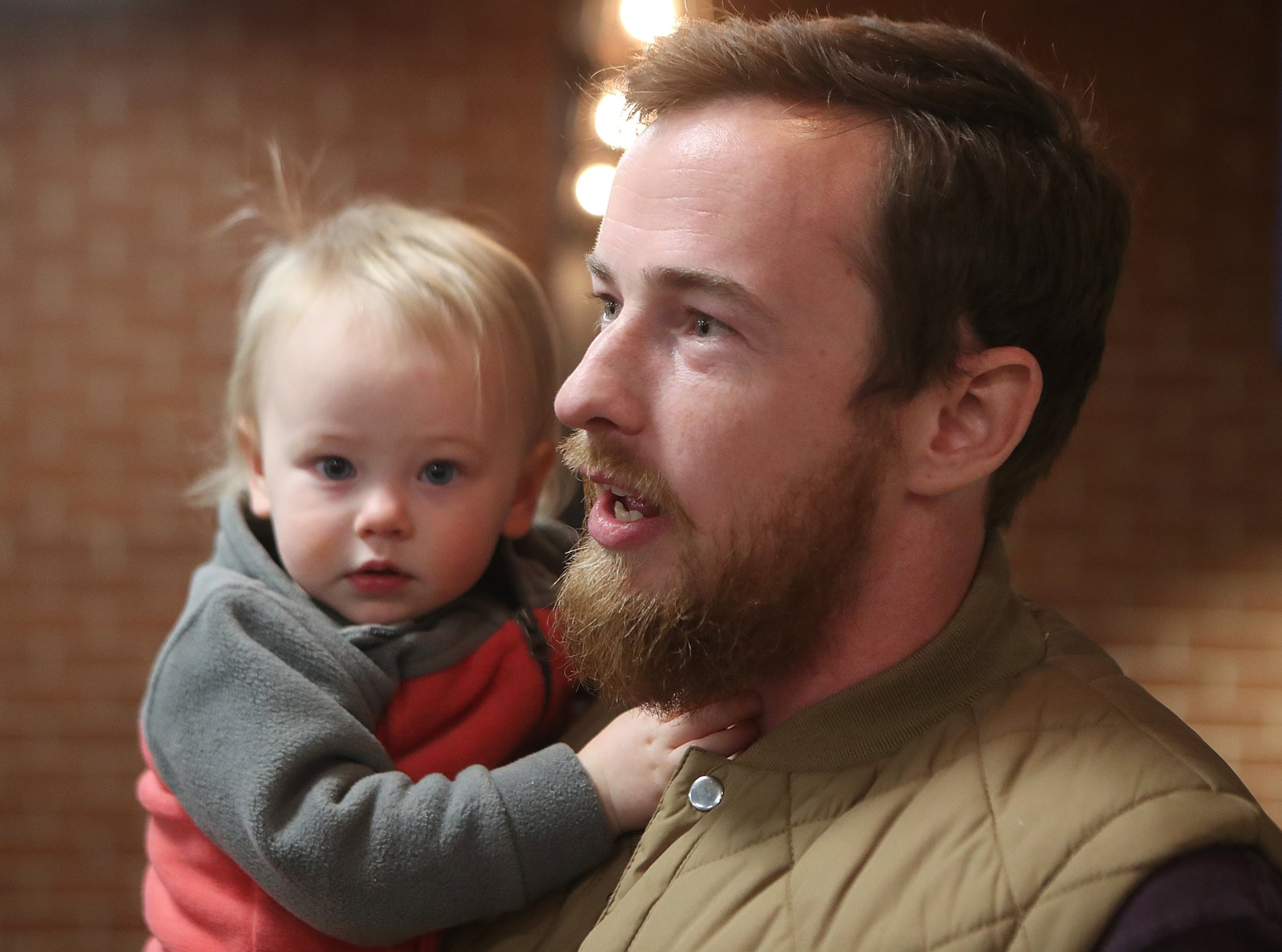 Chip Daymude, with the Department of Agriculture, holds his 18-month-old daughter Penny as he discusses the federal shutdown while relaxing at SweetWater Brewing Company, which was offering free food and beer to furloughed federal workers on Thursday, Jan. 10, 2019, in Atlanta.