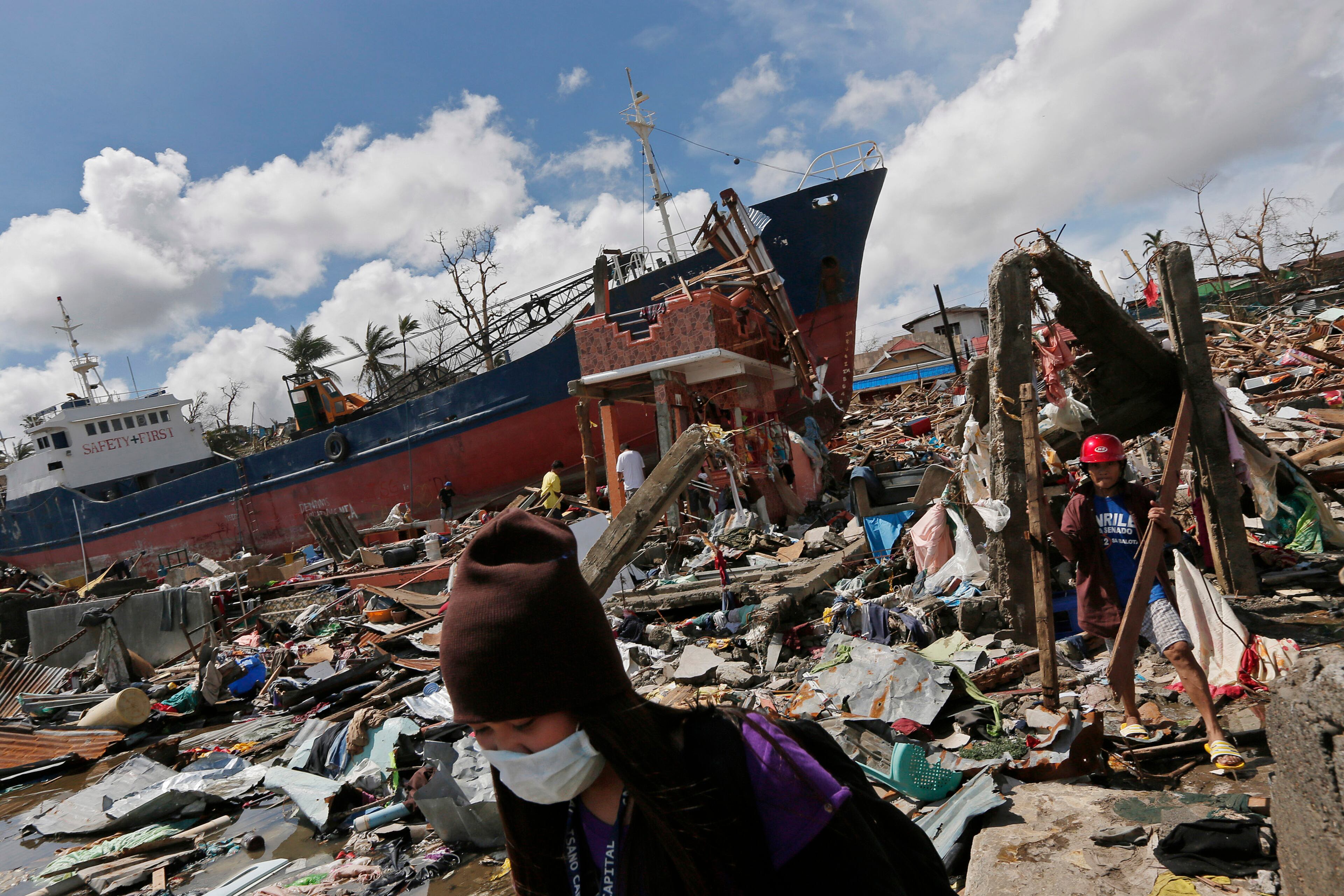 A typhoon survivor walks past a cargo ship which was washed ashore in typhoon ravaged Tacloban city, Leyte province, central Philippines on Wednesday, Nov. 13, 2013. Typhoon Haiyan, one of the strongest storms on record, slammed into central Philippine provinces Friday, leaving a wide swath of destruction.