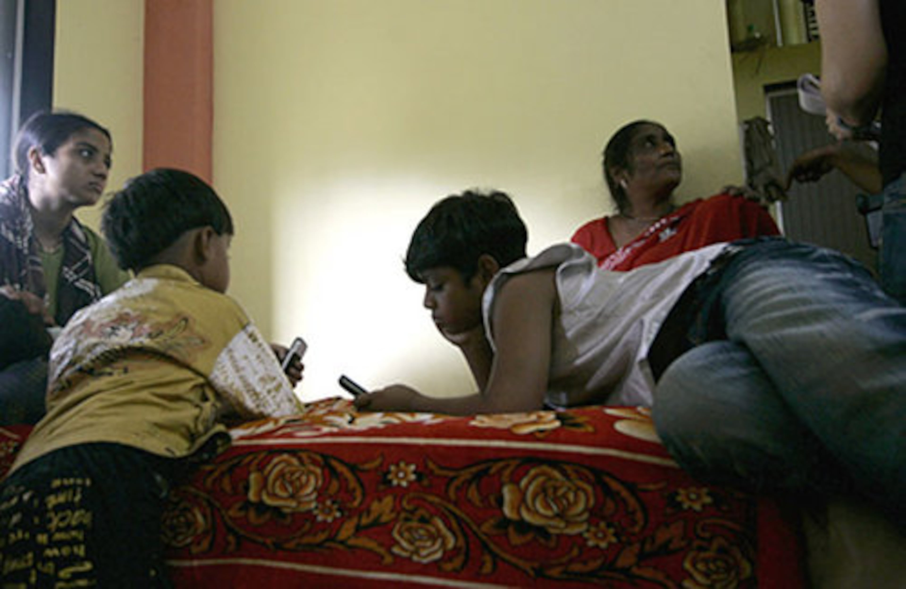 "Slumdog Millionaire" child star Azharuddin Mohammed Ismail, front right, rests on a bed at his new home with friends and family.