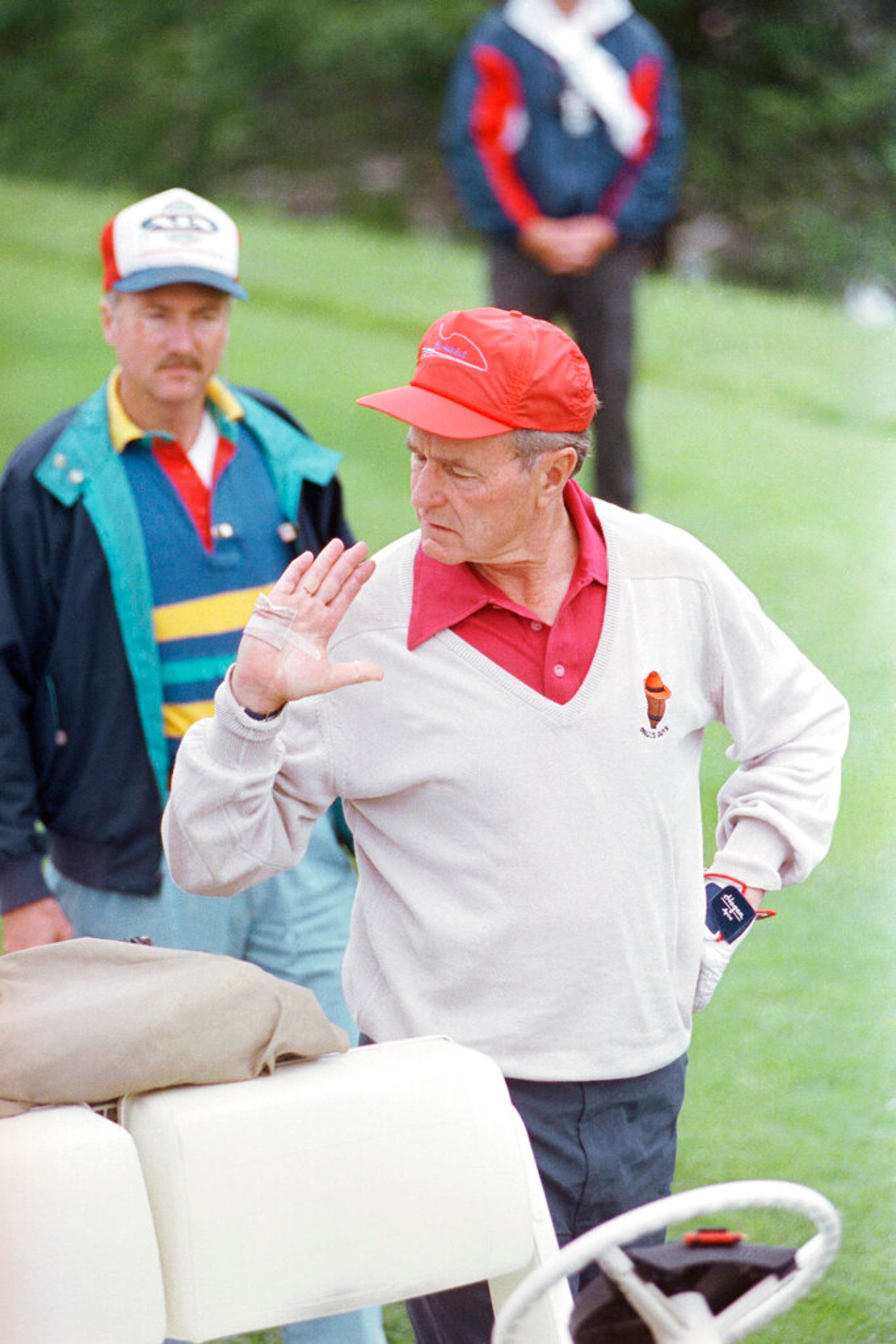 FILE - In this July 4, 1990 file photo, President George H. Bush checks his bandaged hand before starting a round of gold at the Cape Arundel Golf Club in Kennebunkport, Maine. The president said he cut his hand while cleaning fish he caught the day before. (AP Photo/Ron Edmonds)