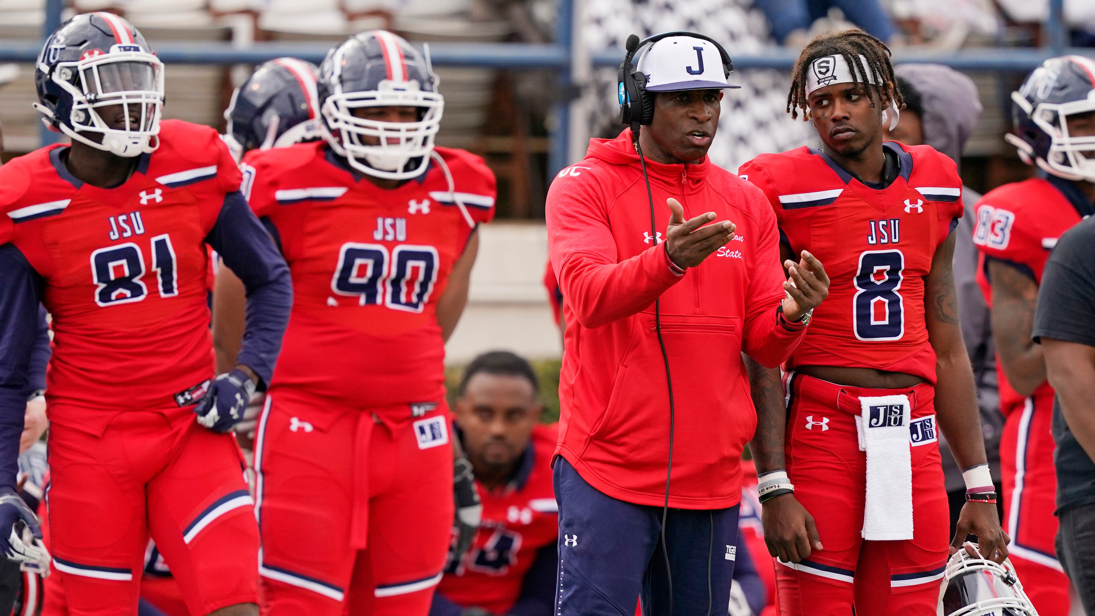 Jackson State football coach Deion Sanders (second from right) confers with quarterback Quincy Casey (8) as tight end Robert Washington Jr. (81) and defensive lineman Brian Mitchell (90) listen in during the second half of game against Edward Waters Sunday, Feb. 21, 2021, in Jackson, Miss. (Rogelio V. Solis/AP)