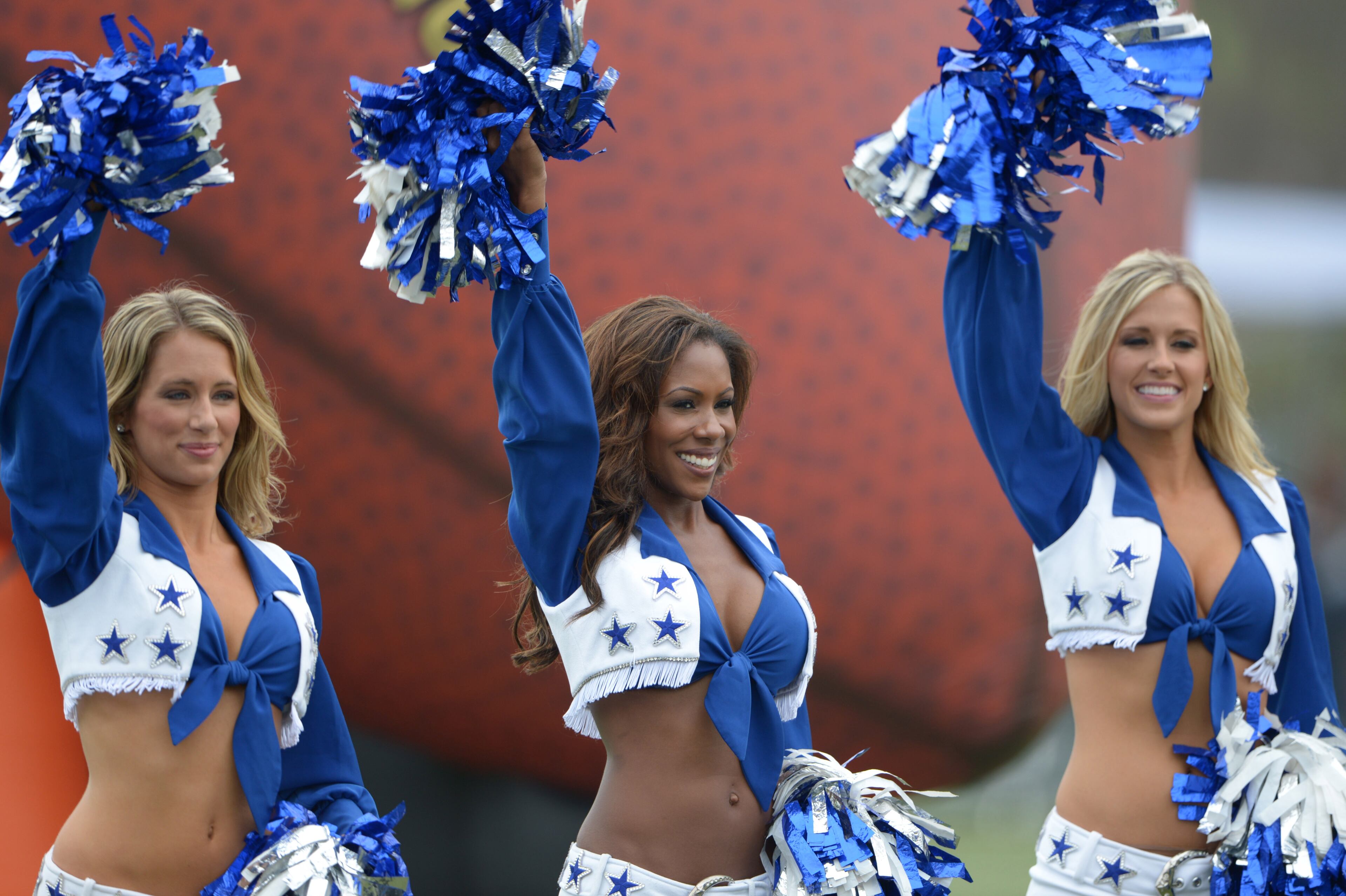 Three Cowboys cheerleaders support the team.