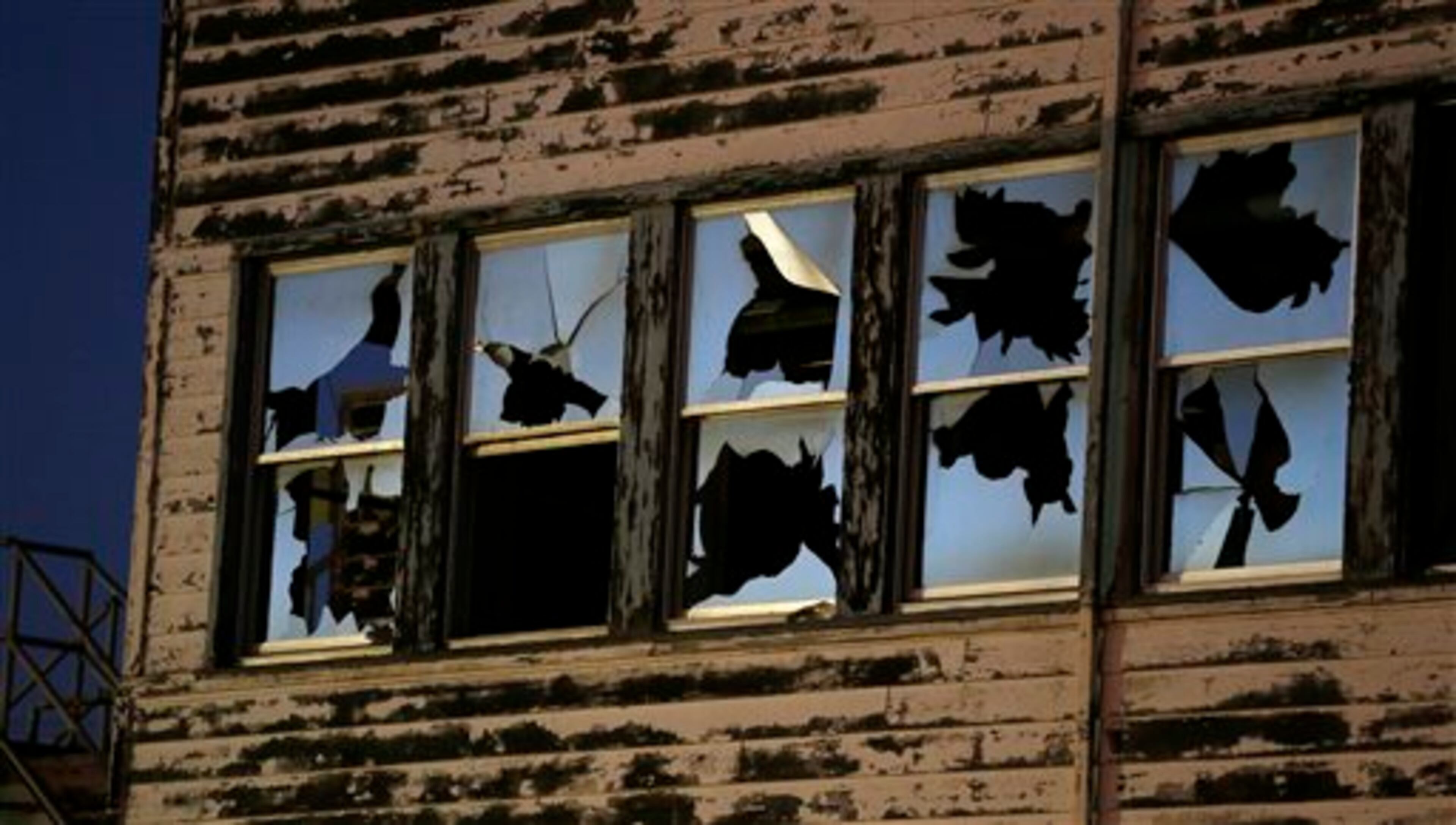 In this Oct. 2, 2014, dusk falls on the shattered windows of the reemployment center at the former Mare Island Naval Shipyard in Vallejo, Calif. The shipyard dates from the 1850s and was the first U.S. Navy base in the Pacific. At its peak in World War II some 50,000 worked on the island. Today about 4,000 either work, live or go to school there. A number of its buildings and facilities are still empty following the closing of the shipyard in 1996. The building is to be demolished soon. (AP Photo/Eric Risberg)