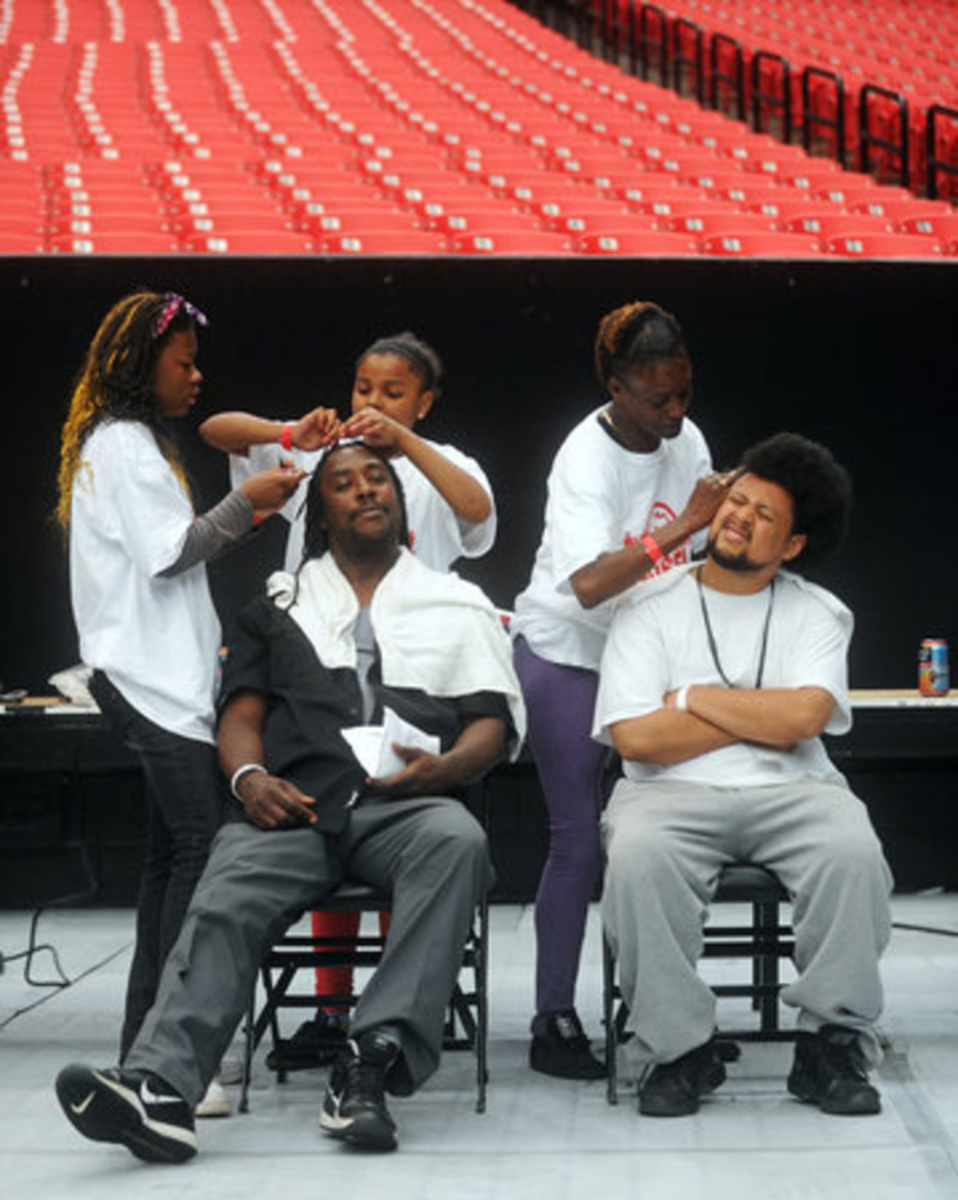 David Edmond (seated, left) and Jonathan Brignoni get their hair done by volunteers (standing from left) Theodoisha McCants, Destiny Williams and Cheryl Swanson.
