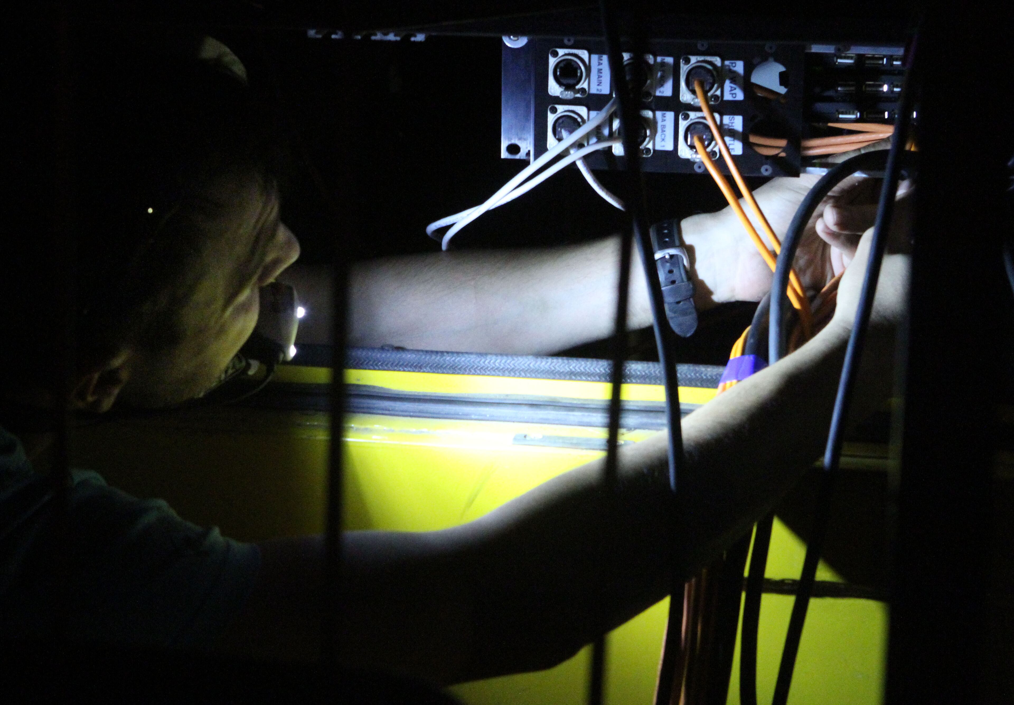John Mytyk holds a flashlight in his mouth as he fixes a video connection while artists rehearse for Cirque du Soleil's "Totem." The title “Totem” is symbolic, connoting the order of the species, how humanity rose from the primordial swamp all the way to the lofty heights of the thunderbird that tops many of the hand-carved poles.