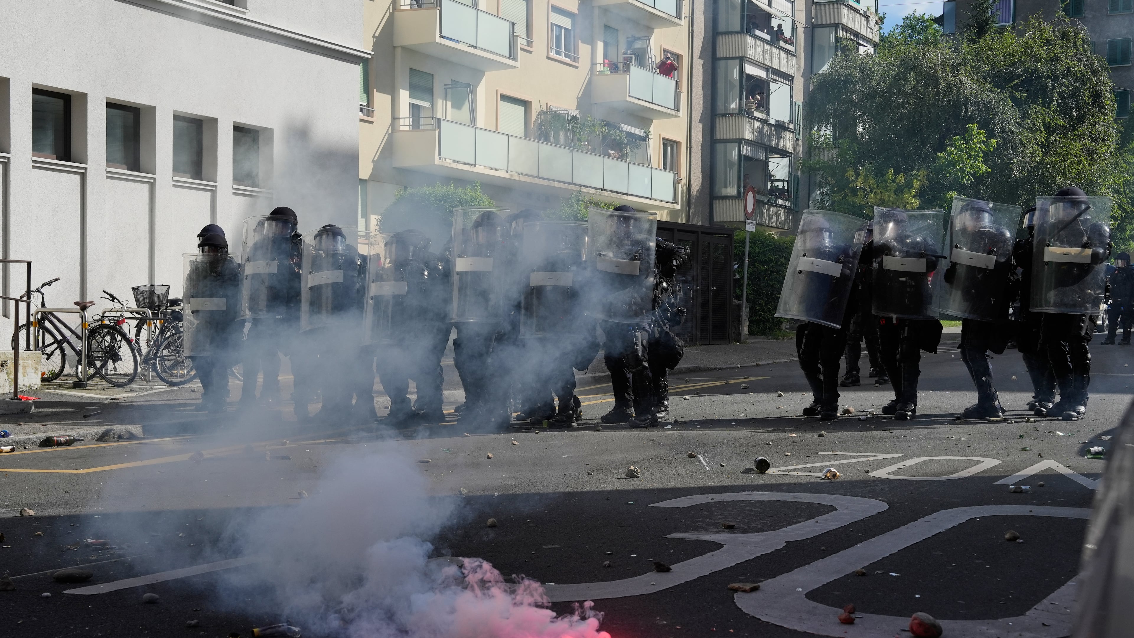 Police form a line in front of a burning flare during a "No G7" demonstration in Geneva, Switzerland, Sunday, June 14, 2026, ahead of the G7 summit scheduled to take place June 15-17. (AP Photo/Baz Ratner)