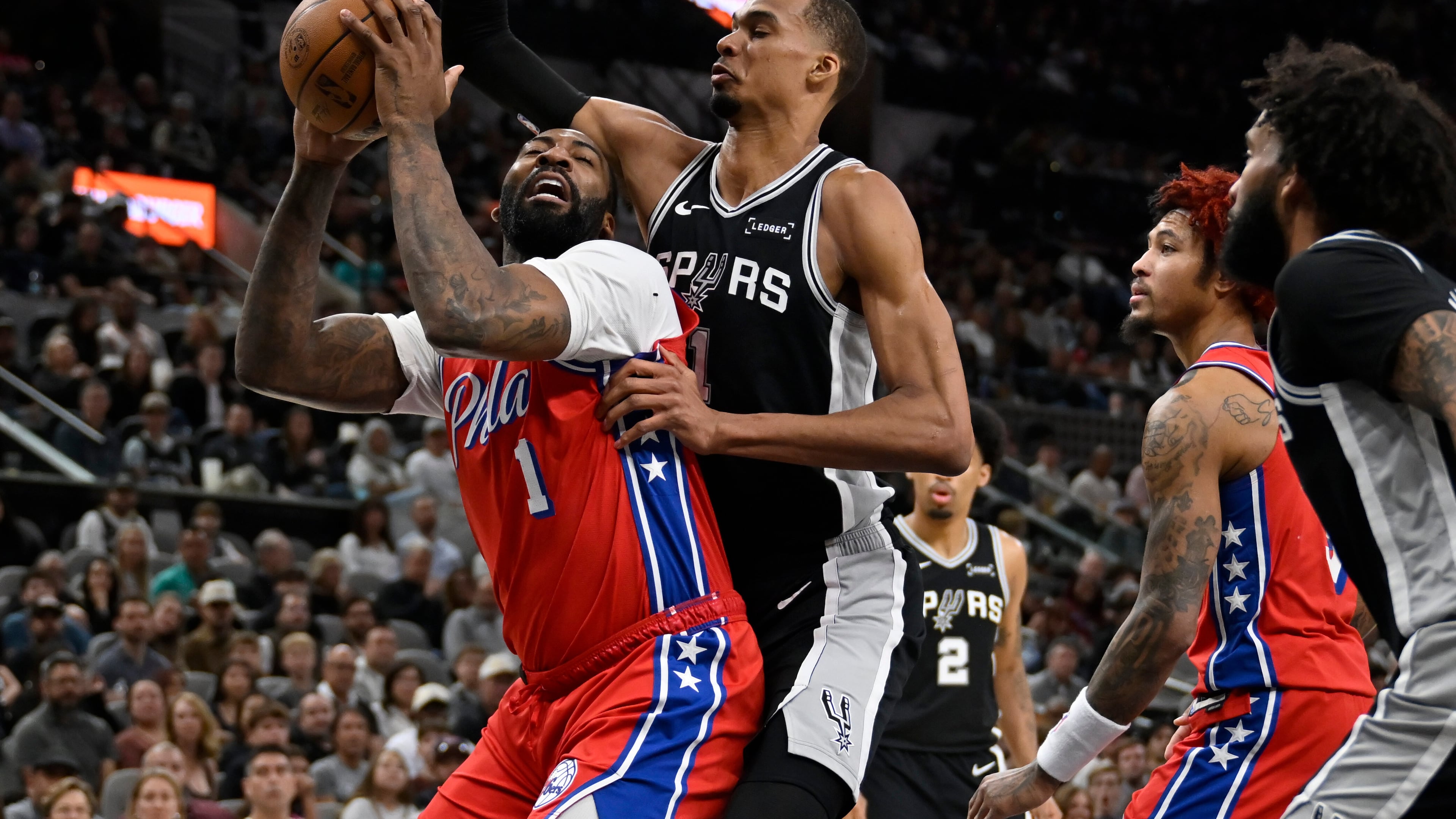 Philadelphia 76ers center Andre Drummond, left, tangles with San Antonio Spurs center Victor Wembanyama during the first half of an NBA basketball game, Monday, April 6, 2026, in San Antonio. (AP Photo/Darren Abate)