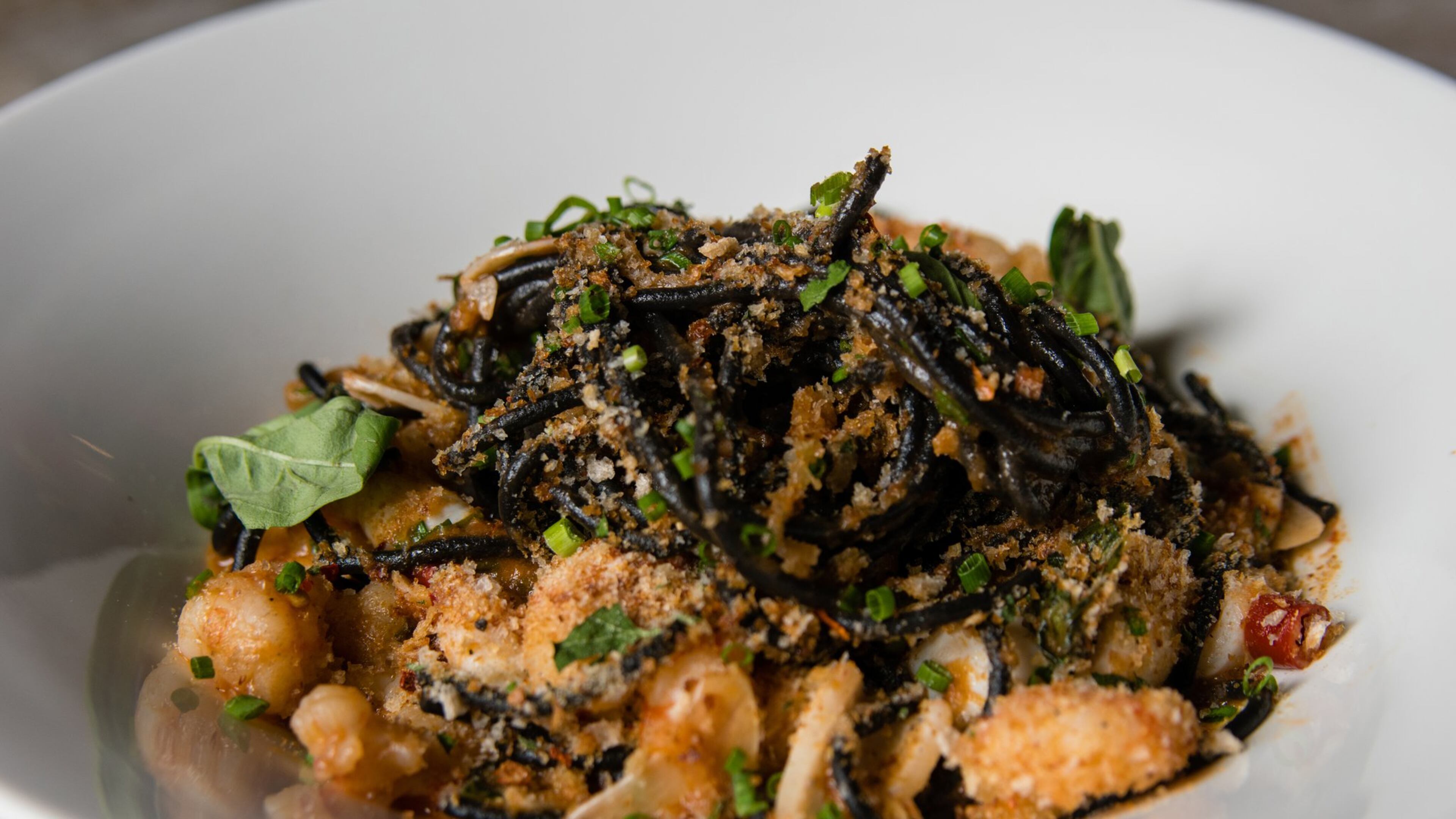 Squid Ink Tonnarelli at Bar Americano dresses a bed of long, black noodles with rock shrimp, calamari, garlic, basil and breadcrumbs. CONTRIBUTED BY HENRI HOLLIS