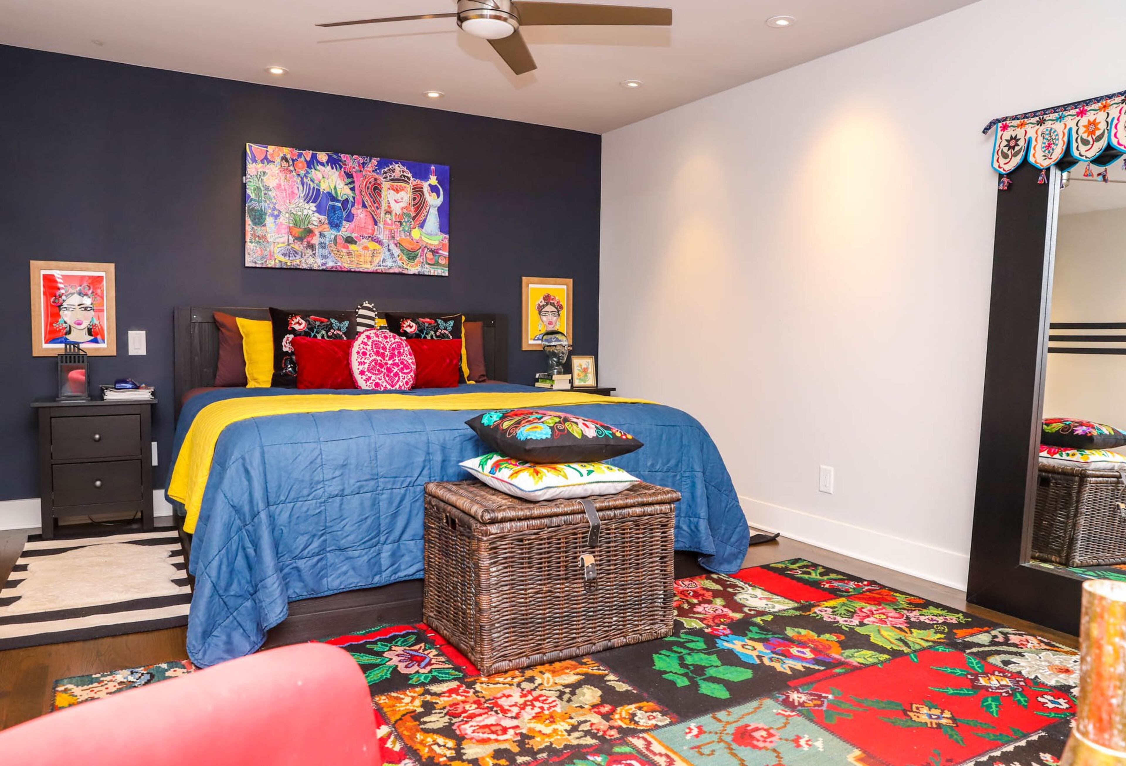 The master bedroom of Jeff and Paola Roder’s home has more muted colors than the common areas, with a color palette inspired by portraits of Frida Kahlo that hang on either side of the bed, both painted by Heather Felder, a Mexican and Norwegian artist. Over the bed hangs a vivid piece from Great Big Canvas, and the rug on the floor is a Turkish line from Ikea. Text by Shannon Dominy. Photo by Reynolds Rogers.