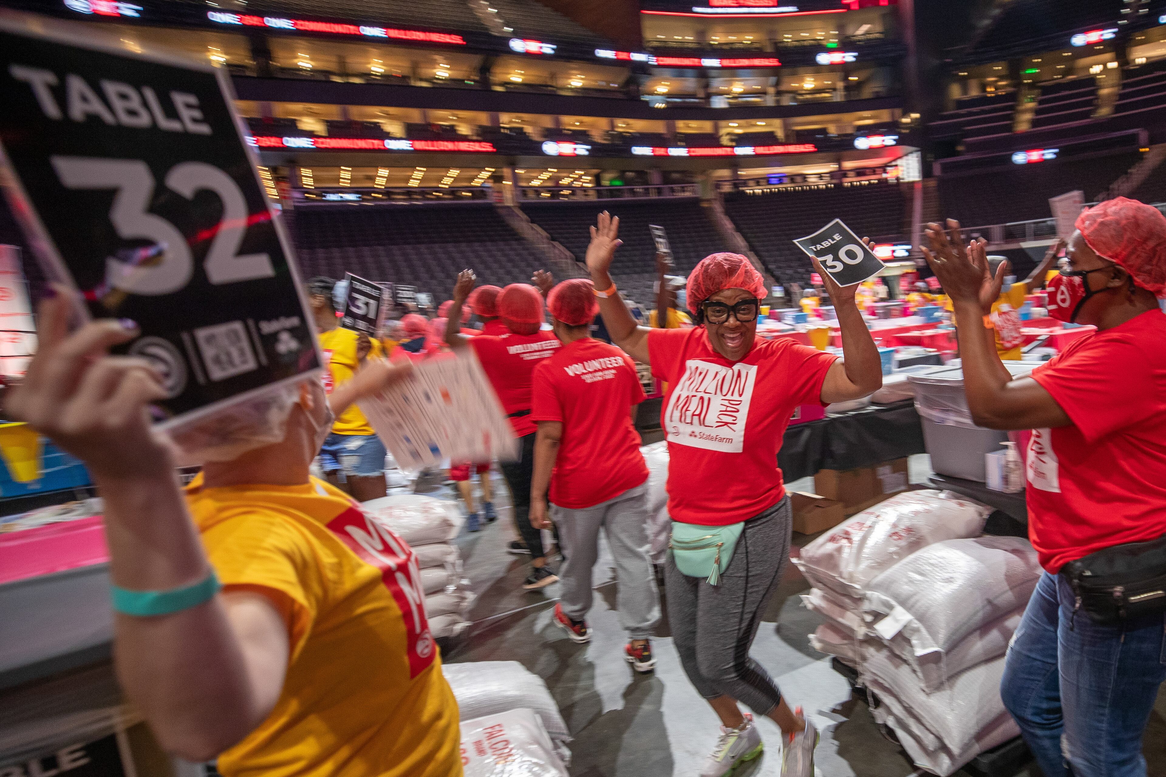 Volunteers celebrate as they enter the State Farm Arena during the Million Meal Pack event on Saturday, July 16, 2022. (Steve Schaefer / steve.schaefer@ajc.com)