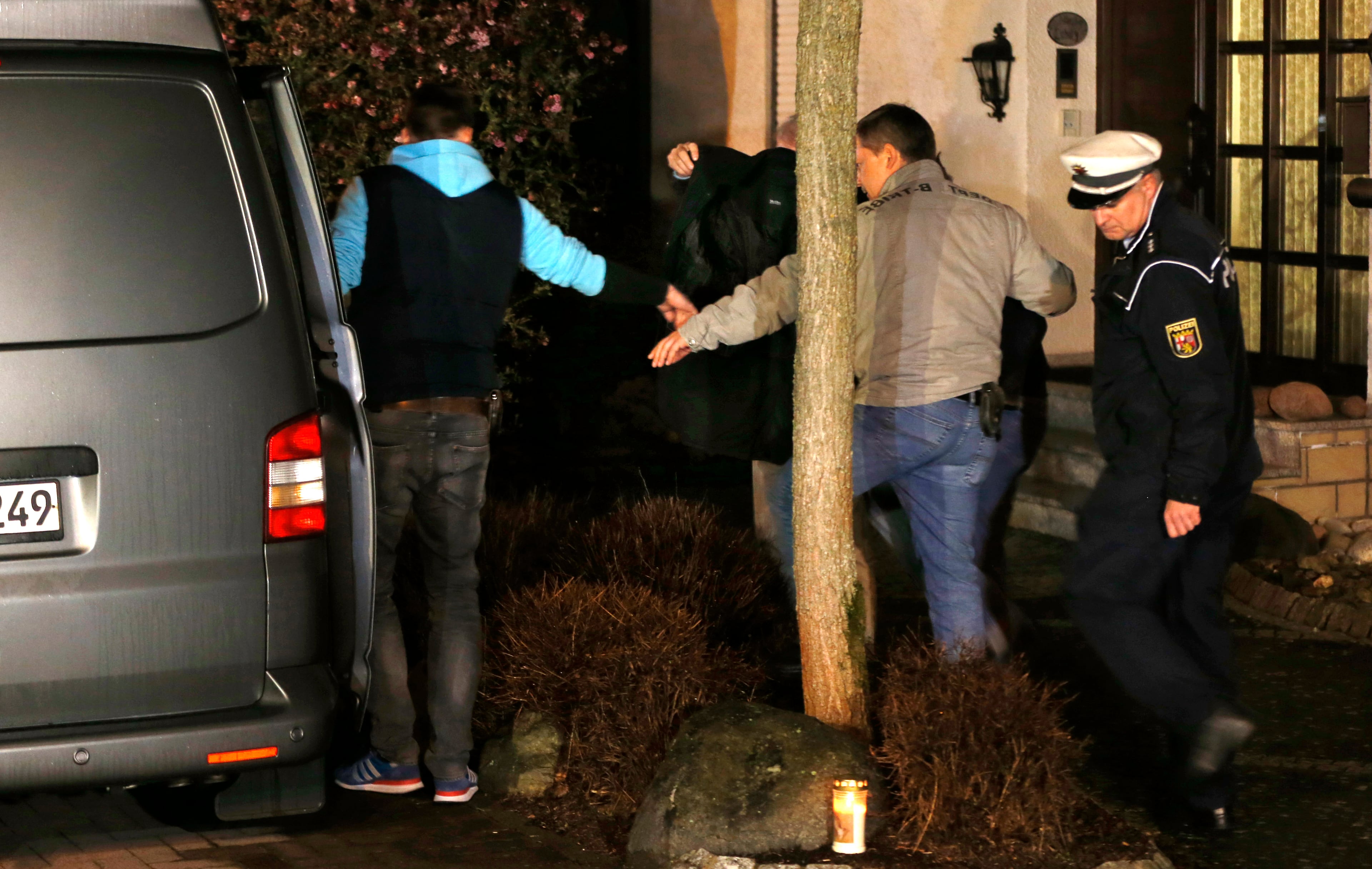 A person covered with a black blanket is led by police officers from the hours of the family of Andreas Lubitz to a police van in Montabaur, Germany, Thursday, March 26, 2015. Lubitz was the copilot on flight Germanwings 9525 that crashed with 150 people on board on Tuesday in the French Alps. (AP Photo/Michael Probst)