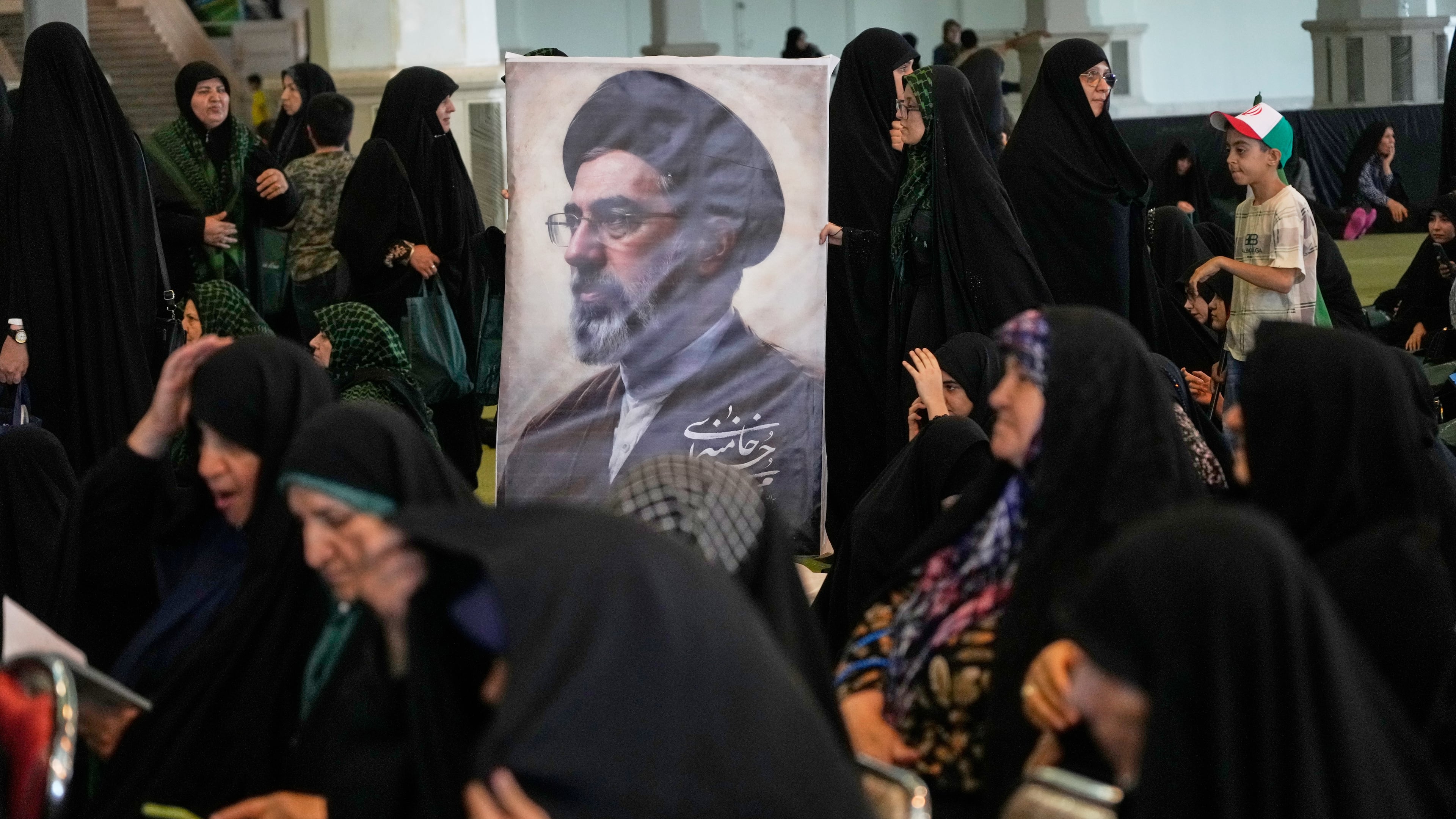 Women gather around a portrait of Iran's Supreme Leader, Ayatollah Mojtaba Khamenei, during a ceremony honoring the armed forces and those killed in the war with Israel and the U.S. at the Imam Khomeini Grand Mosque in Tehran, Iran, Sunday, May 24, 2026. (AP Photo/Vahid Salemi)