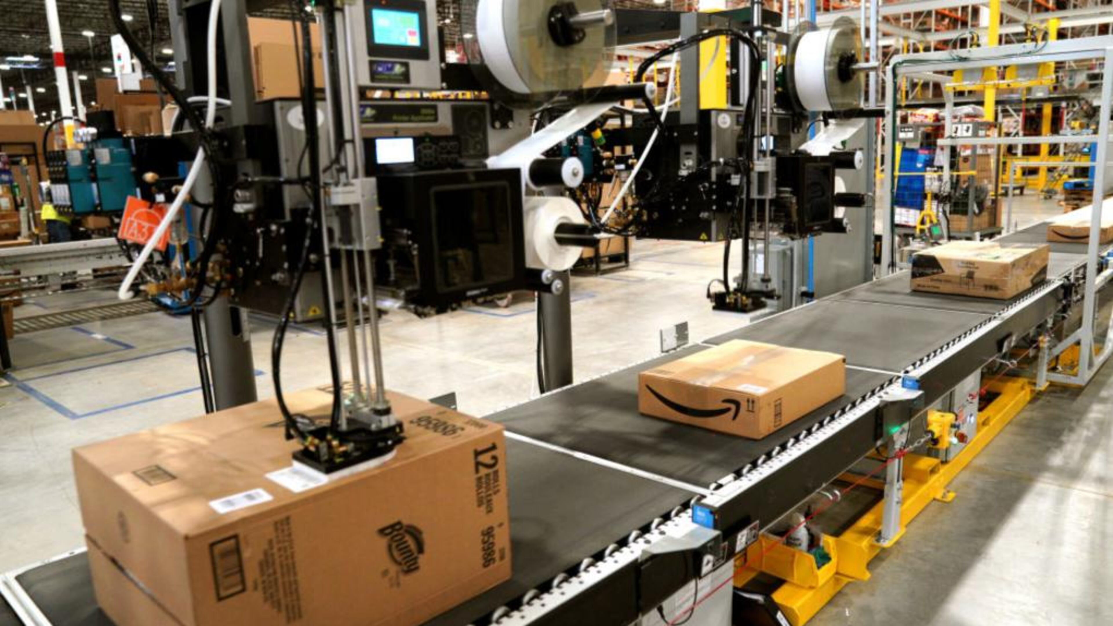 A machine applies shipping lables to packed orders at an Amazon fulfillment center.