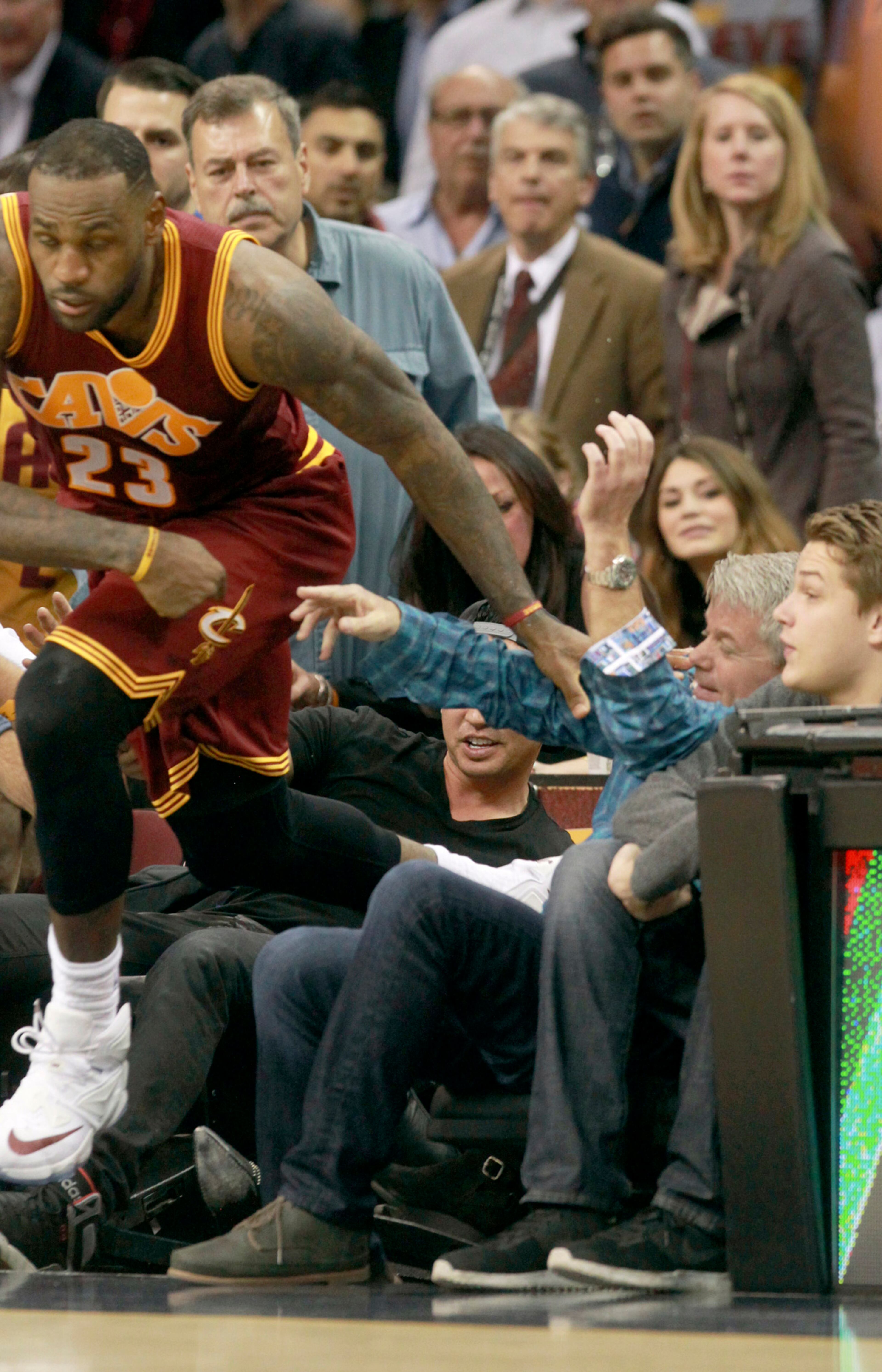 The Cleveland Cavaliers' LeBron James emerges from the front row of fans after going after a loose ball against the Oklahoma City Thunder on Thursday, Dec. 17, 2015, at Quicken Loans Arena in Cleveland. James crashed into the wife of PGA golfer Jason Day, who had to be taken from courtside by stretcher. (Phil Masturzo/Akron Beacon Journal/TNS)
