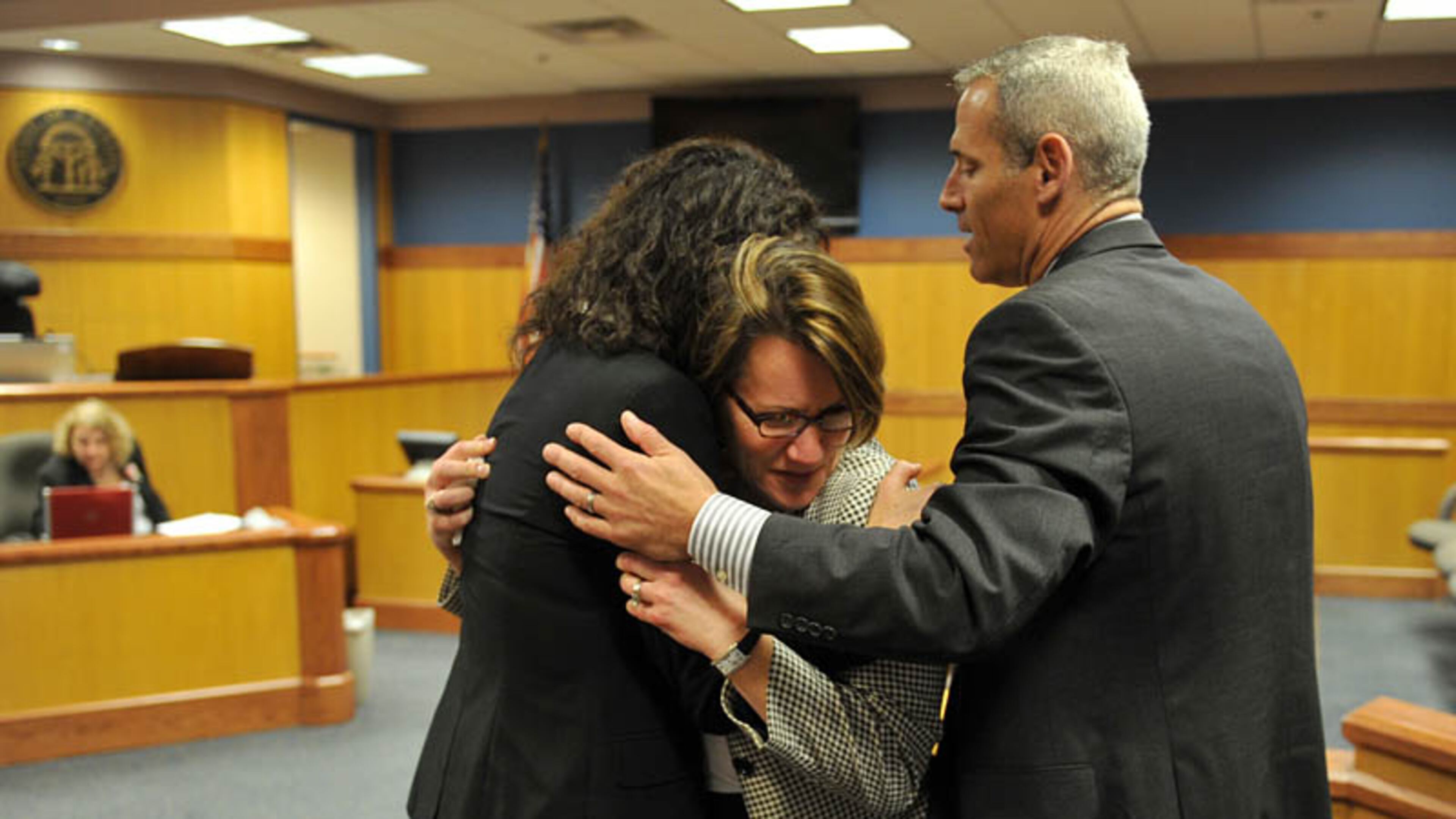 Stacey Kalberman, center is hugged by her attorney Kimberly Worth, left, and husband Neil after winning a whistle blower suit against the state ethics commission. The former state ethics commission executive director sued after she claimed she was forced from her position after investigating Gov. Nathan Deal's campaign.