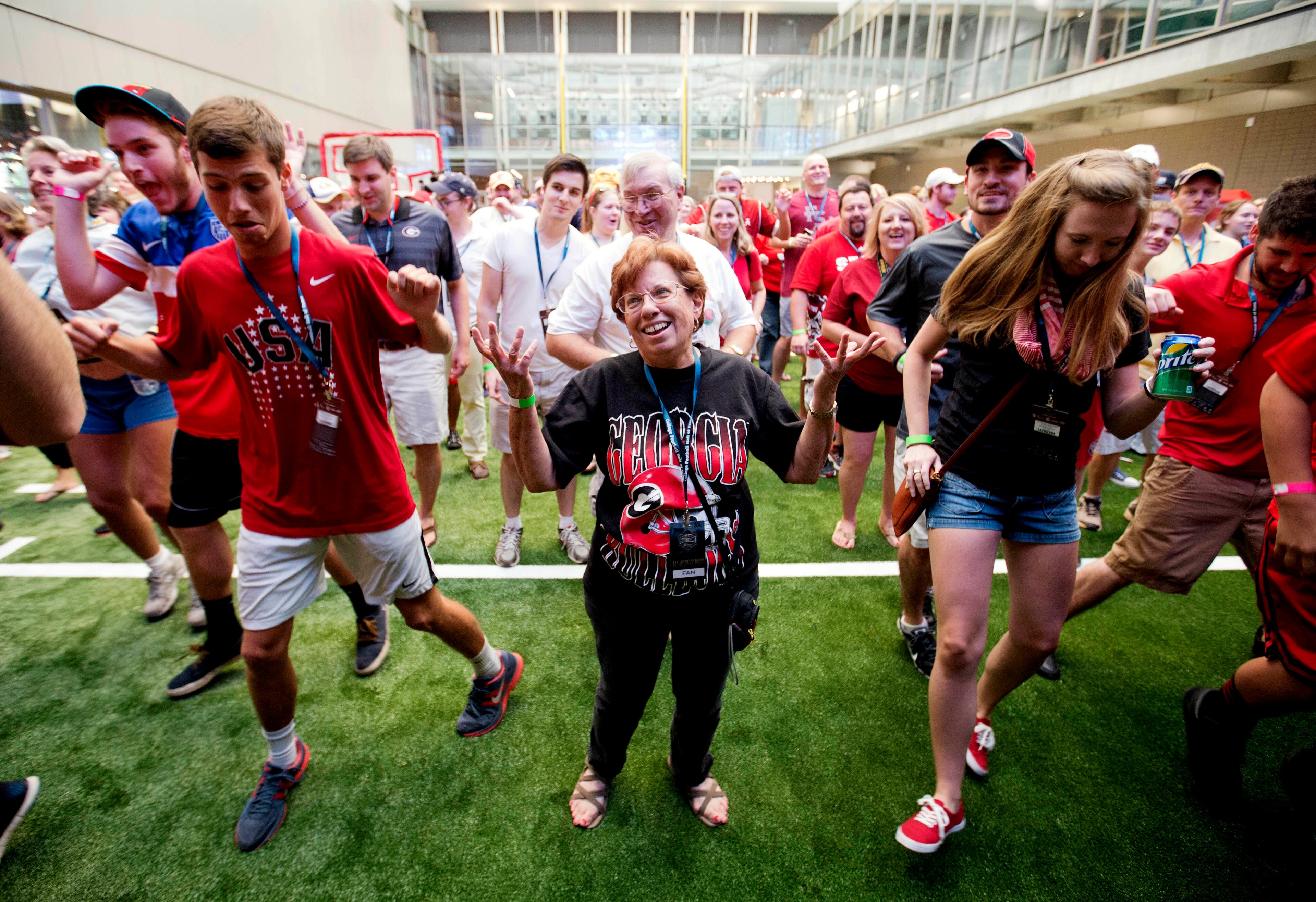 Lyn Grossman, of Smyrna Ga., throws her hands up in the air while trying to keep up with a dance move during a sleepover in the College Football Hall of Fame, Wednesday, Aug. 13, 2014, in Atlanta. Guests competed in dance competitions to win prizes before taking a tour of the museum. (AP Photo/David Goldman)