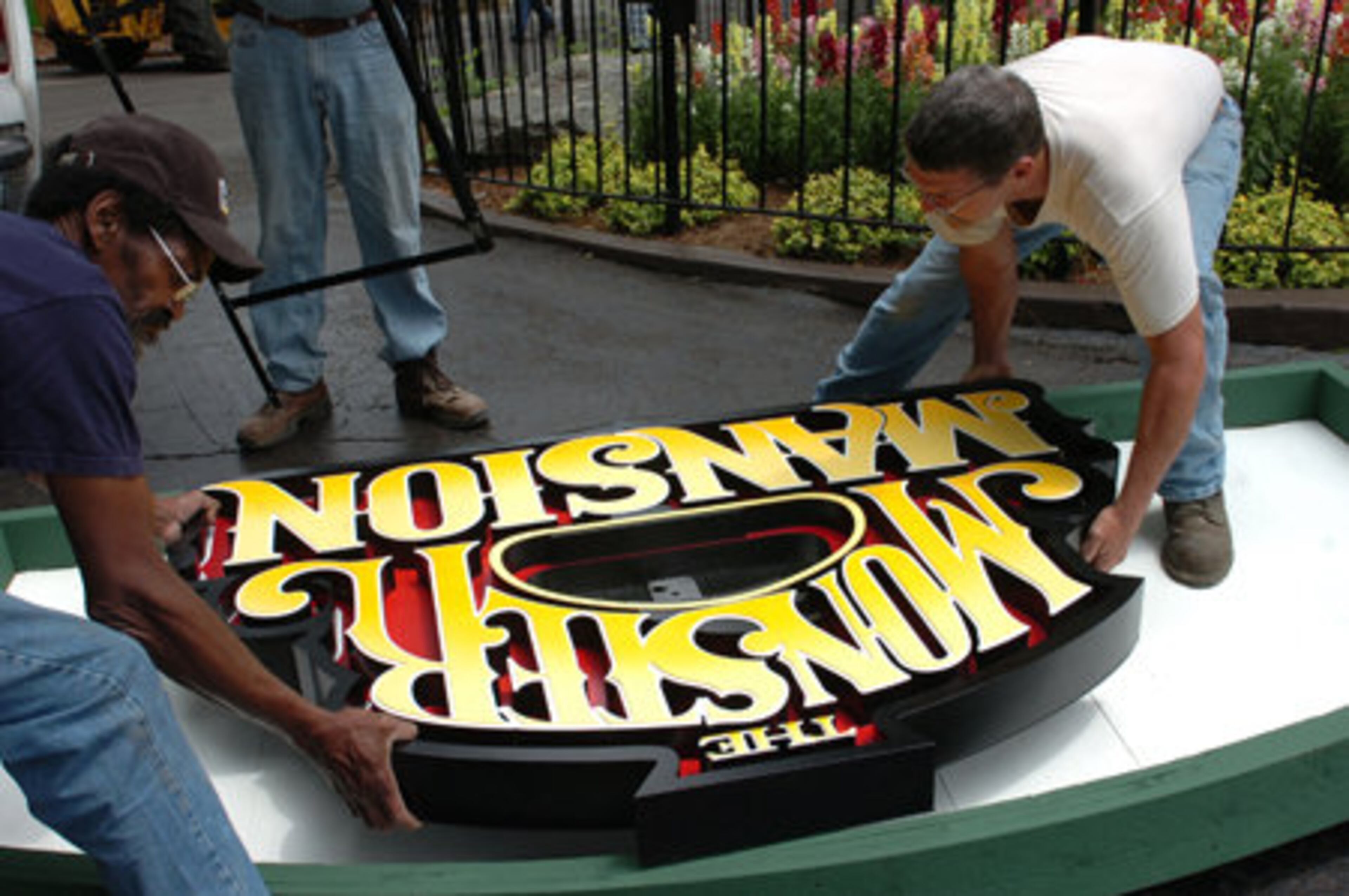 Six Flags Over Georgia is reopening the family-friendly classic Monster Plantation on Saturday with a new name and a new look. Tim High and Charles Love work on a sign at the renamed Monster Mansion.