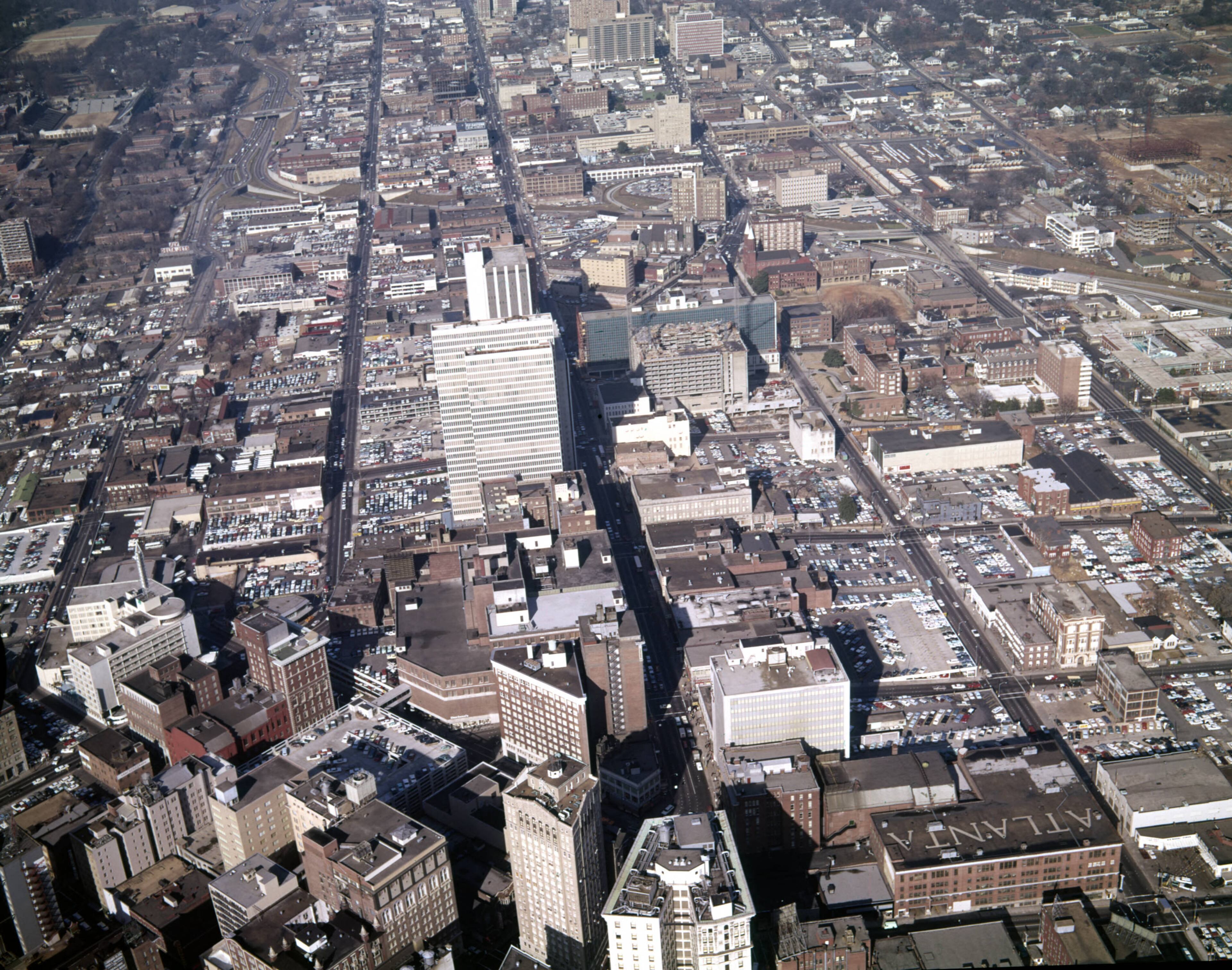 Aerial view of downtown, looking north, showing large areas covered in parking lots, Atlanta, Georgia, December 21, 1965. From the negative envelope: Negative envelope: "Atlanta Parking Lots and Shopping Centers. 12-21-65. F. Jillson." The central street running north is Peachtree Street.