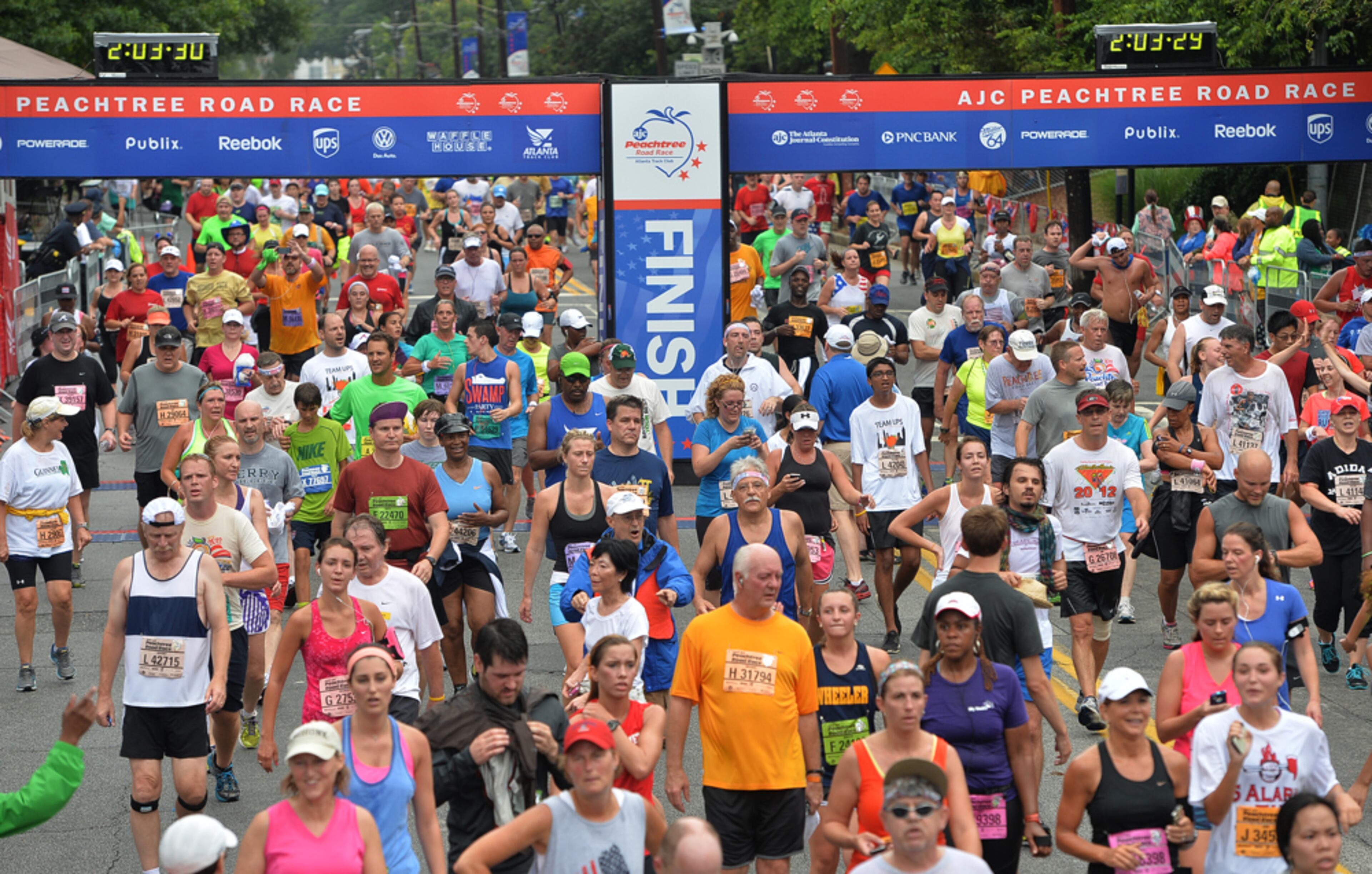 60,000 STRONG--July 4, 2013 -ATLANTA: Runners cross the finish line at 2:03.30 during the AJC Peachtree Road Race on Thursday, July 4,2013, at Piedmont Park. Sixty thousand runners completed the 10k race. Runners burned approximately 36 million calories and the average age for this year's Peachtree participant was 40. JOHNNY CRAWFORD / JCRAWFORD@AJC.COM