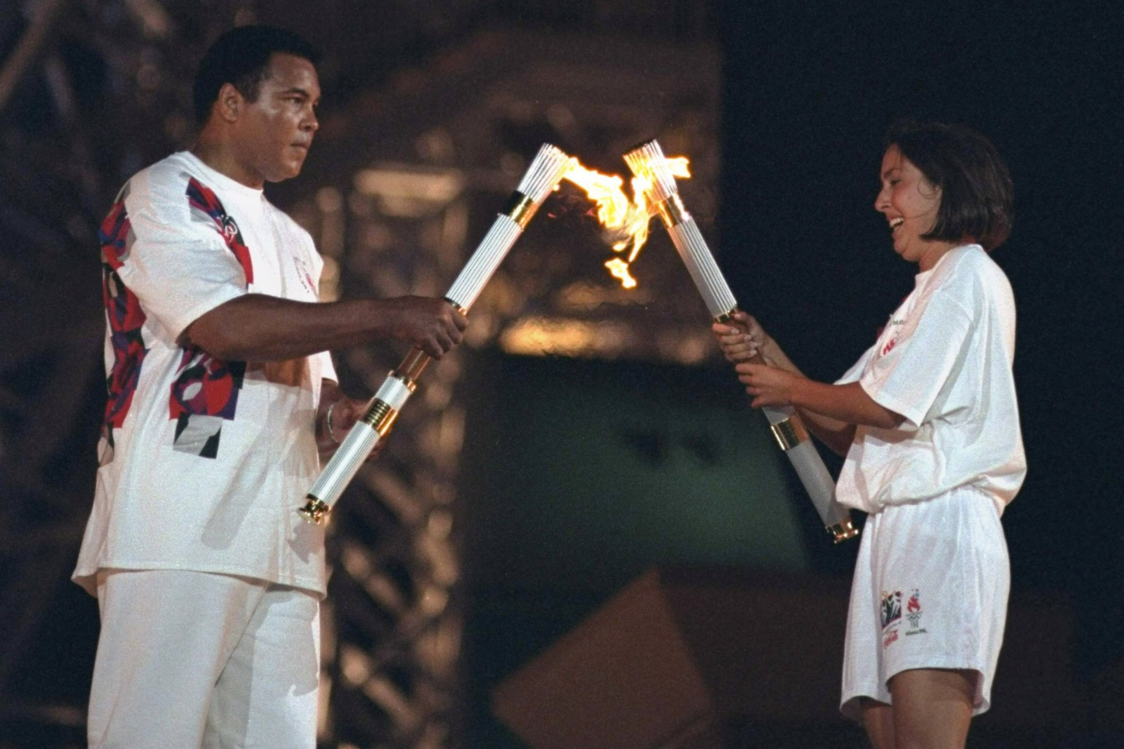 Olympic swimmer Janet Evans (right) passes the Olympic flame to boxing legend Muhammad Ali at the 1996 Atlanta Games. (Courtesy of Lynn Johnson/Sports Illustrated)
