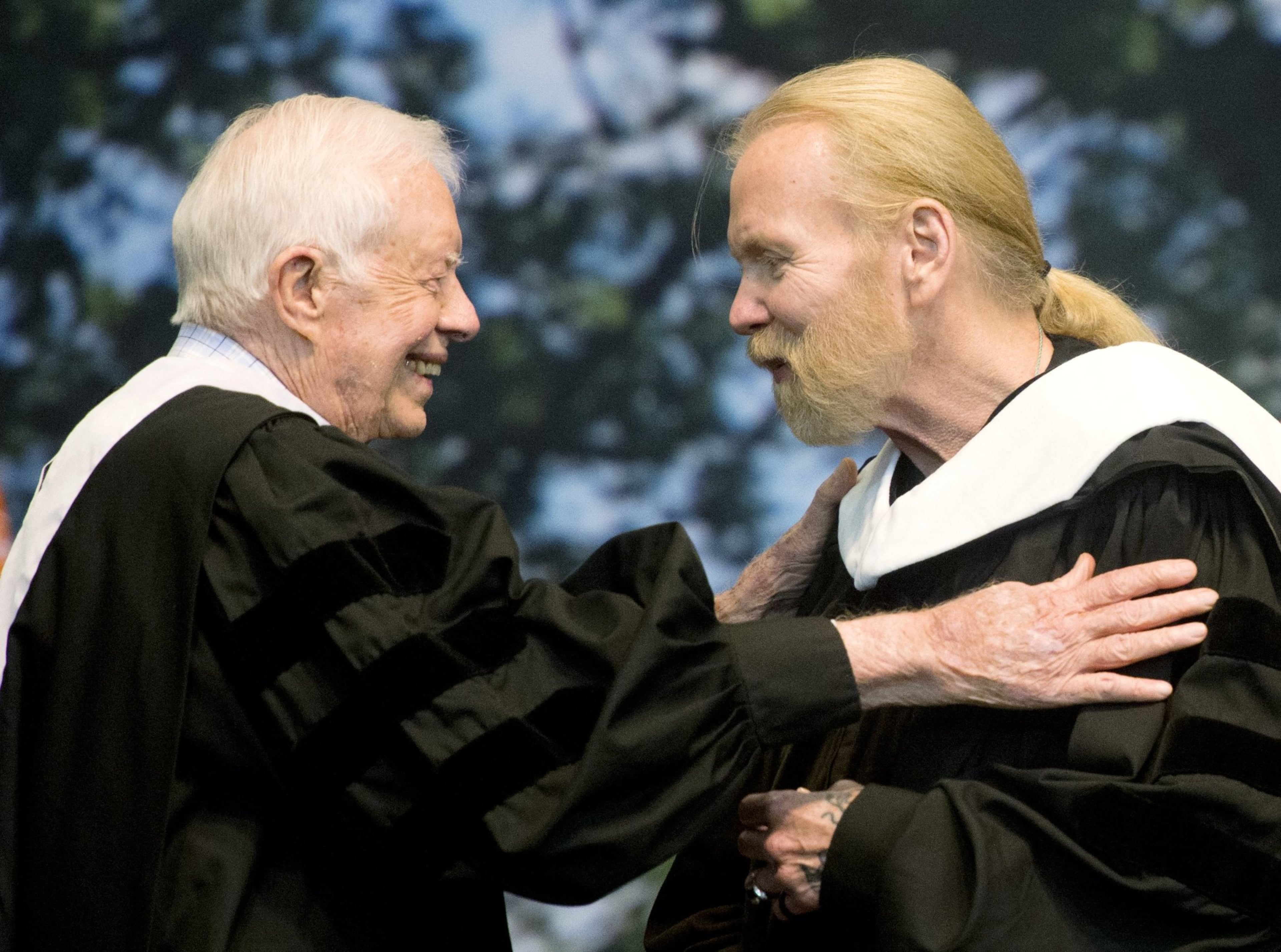 Former President Jimmy Carter and Rock and Roll Hall of Famer Gregg Allman embrace while Allman receives an honorary Doctor of Humanities degree during Mercer University’s commencement at Hawkins Arena in Macon, Ga., on Saturday, May 14, 2016. (Jason Vorhees/The Macon Telegraph via AP)