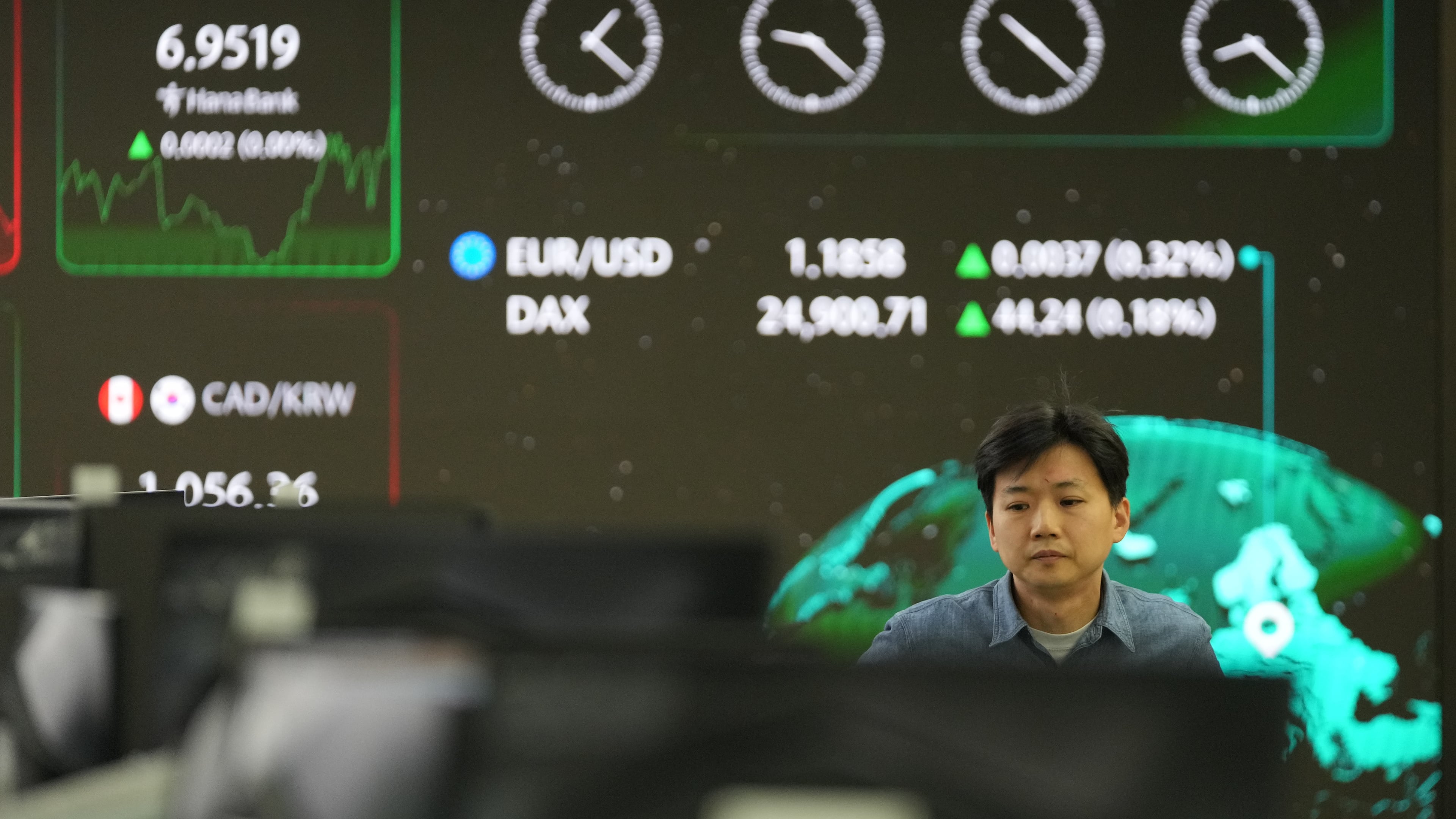 A dealer walks past near the screens showing the foreign exchange rates at a dealing room of Hana Bank in Seoul, South Korea, Monday, Jan. 26, 2026. (AP Photo/Lee Jin-man)