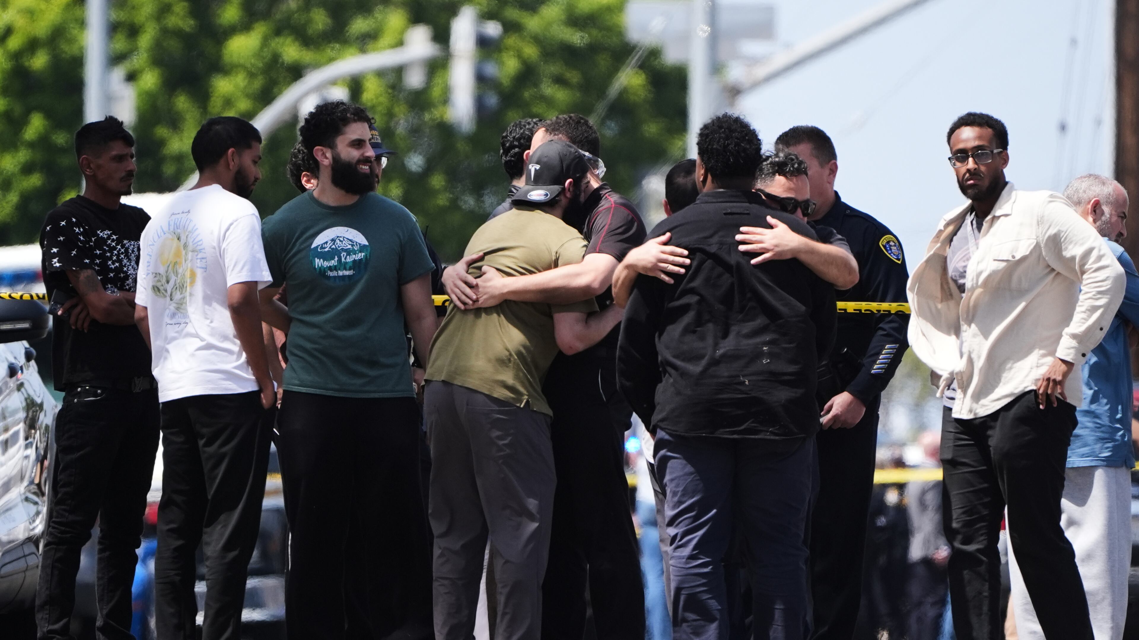People embrace near the scene of a shooting outside the Islamic Center of San Diego Monday, May 18, 2026, in San Diego. (AP Photo/Gregory Bull)