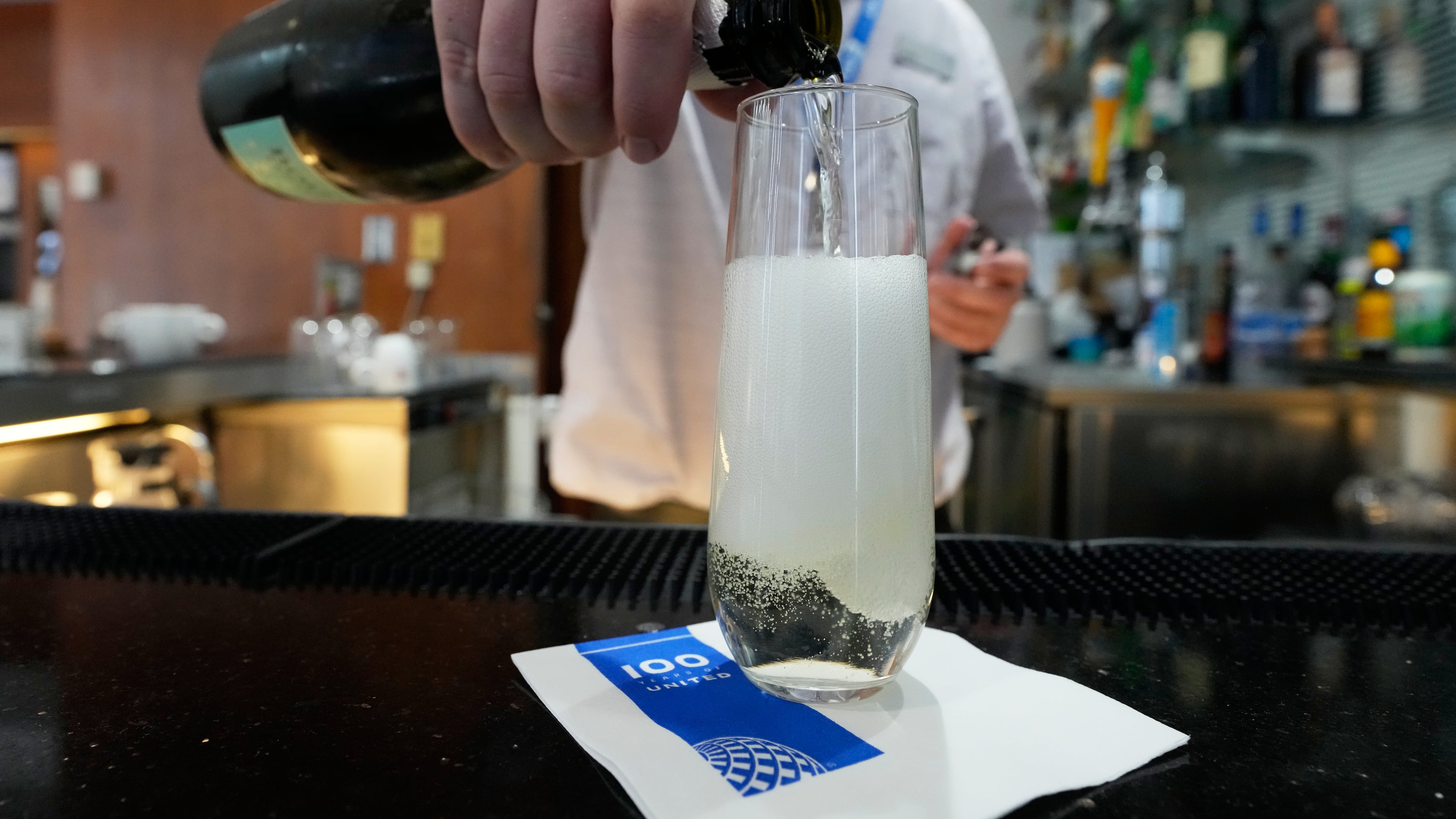 A bartender pours a glass of sparkling wine at the United Club lounge, Monday, June 29, 2026, in Minneapolis, Minn. (AP Photo/Chris Carlson)