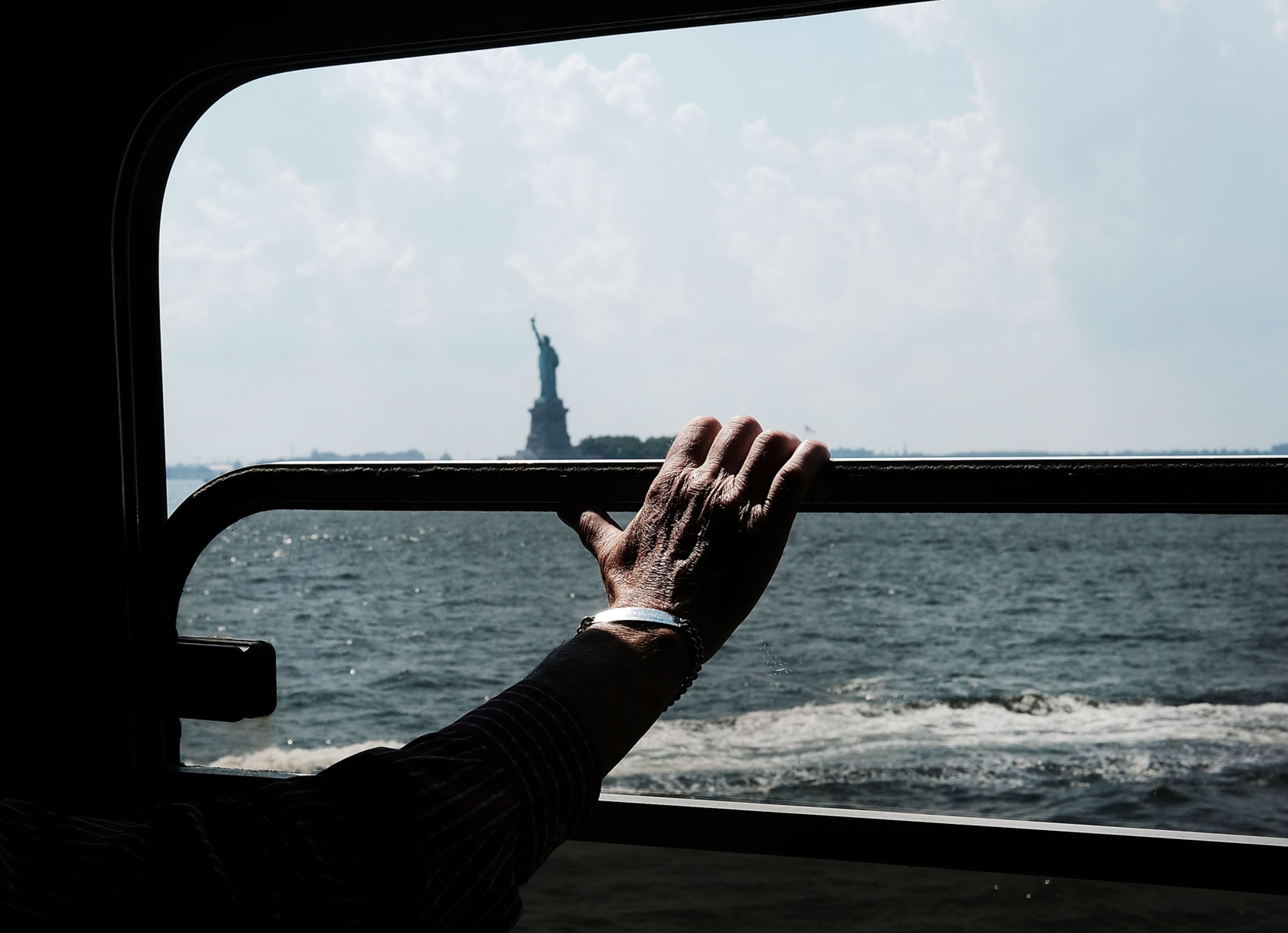 NEW YORK, NY - AUGUST 03: A man looks out at the Statue of Liberty from he Staten Island Ferry on August 3, 2017 in New York City. New York and much of the East Coast has been experiencing days of warm and humid weather with temperatures at or above normal. (Photo by Spencer Platt/Getty Images)