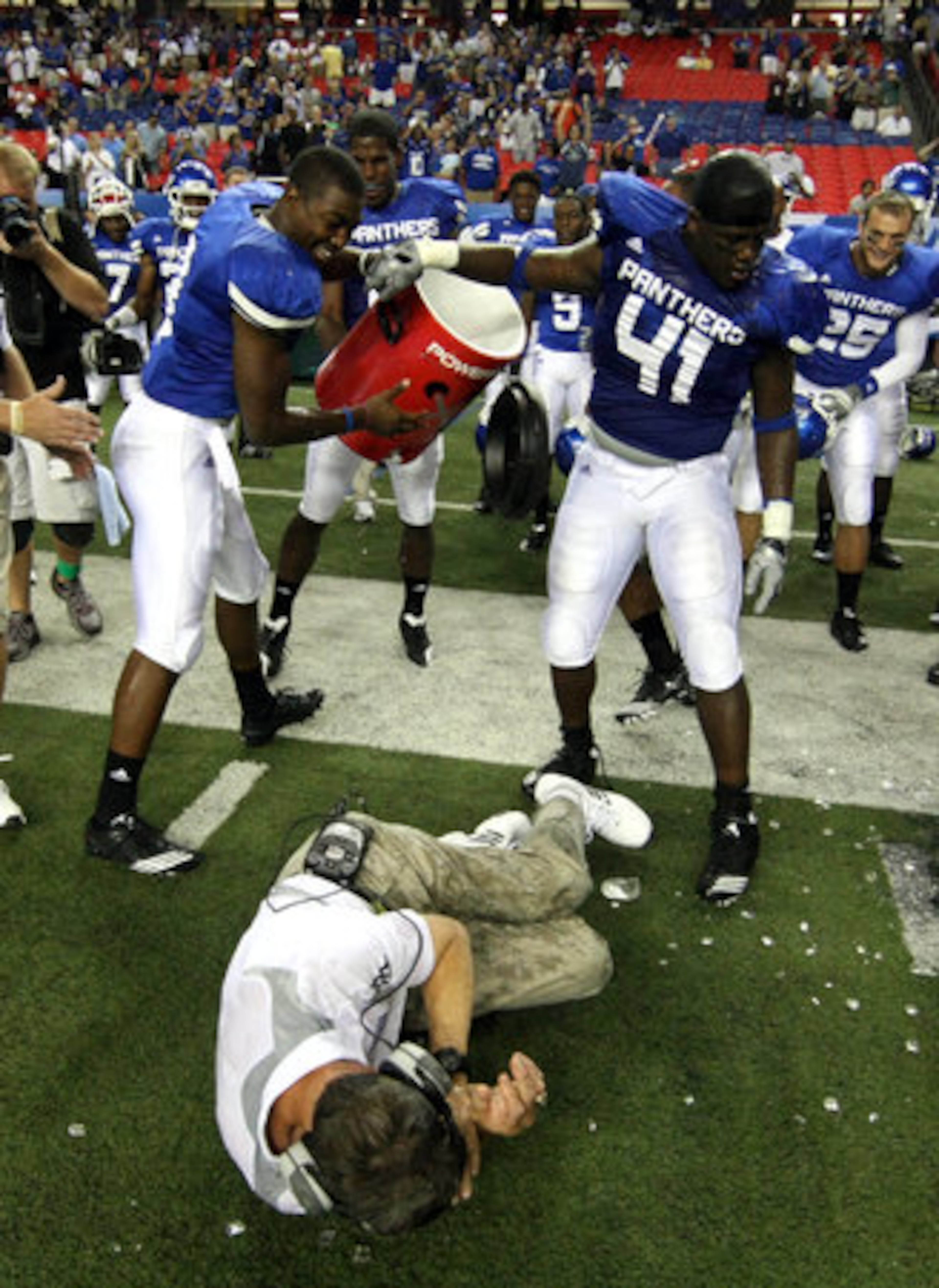Georgia State University coach Bill Curry lays on the ground after getting doused with water by players including Olufemi Opahubi (41) as they celebrate their 41-7 win over Shorter College for their first ever win in the Georgia Dome Thursday night in Atlanta, Ga., Sept. 2, 2010. Curry lay on the ground for a while until he was helped up by assistant coaches.