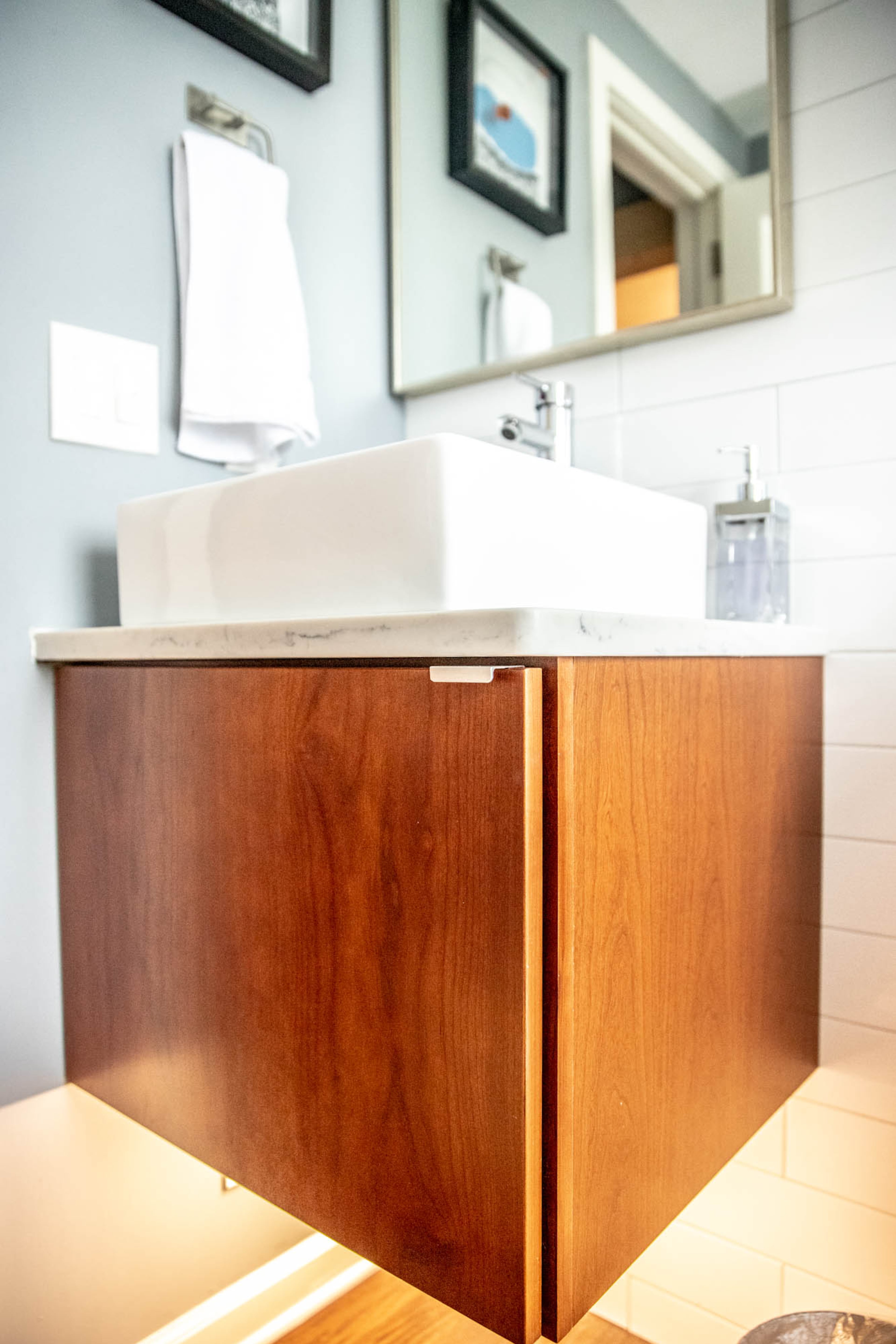 A floating vanity and vessel sink adds style and function while saving space in the downstairs bath of Adam Perry and Ben Ratossa's DeKalb county home. Icefall white subway tile by The Tile Shop gives the small space clean lines.