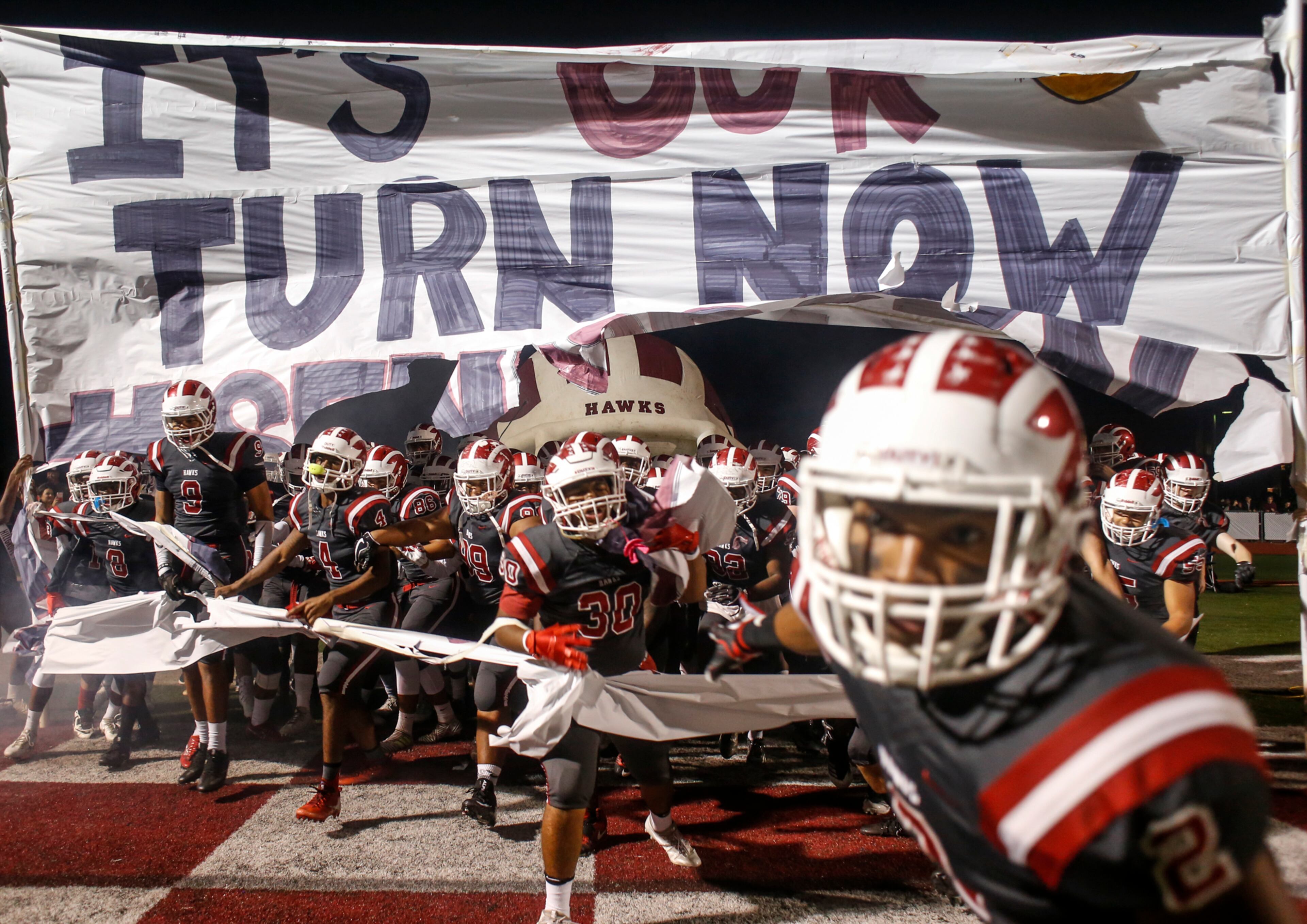 Hillgrove players break through a banner reading "It's Our Turn Now" before a high school football game between the McEachern Indians and the Hillgrove Hawks at Hillgrove High School in Powder Springs, Georgia, on Friday, Nov. 3, 2017. (CASEY SYKES, CASEY.SYKES@AJC.COM)
