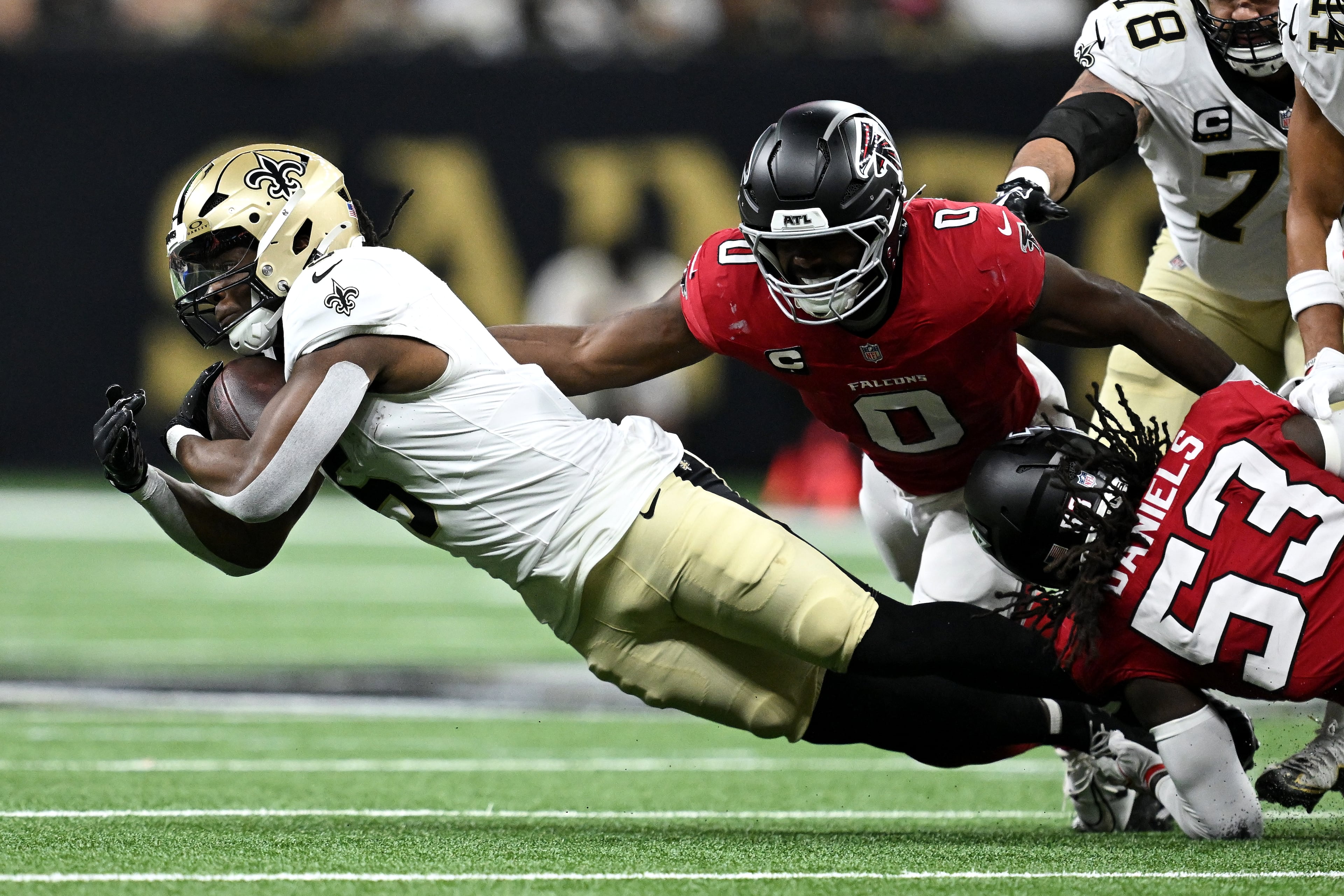 New Orleans Saints running back Kendre Miller (left) runs against Atlanta Falcons linebacker Divine Deablo (second from right) and linebacker Kendal Daniels (bottom right) during the first half of an NFL football game in New Orleans, Monday, Oct. 5, 2026. (Ella Hall/AP)