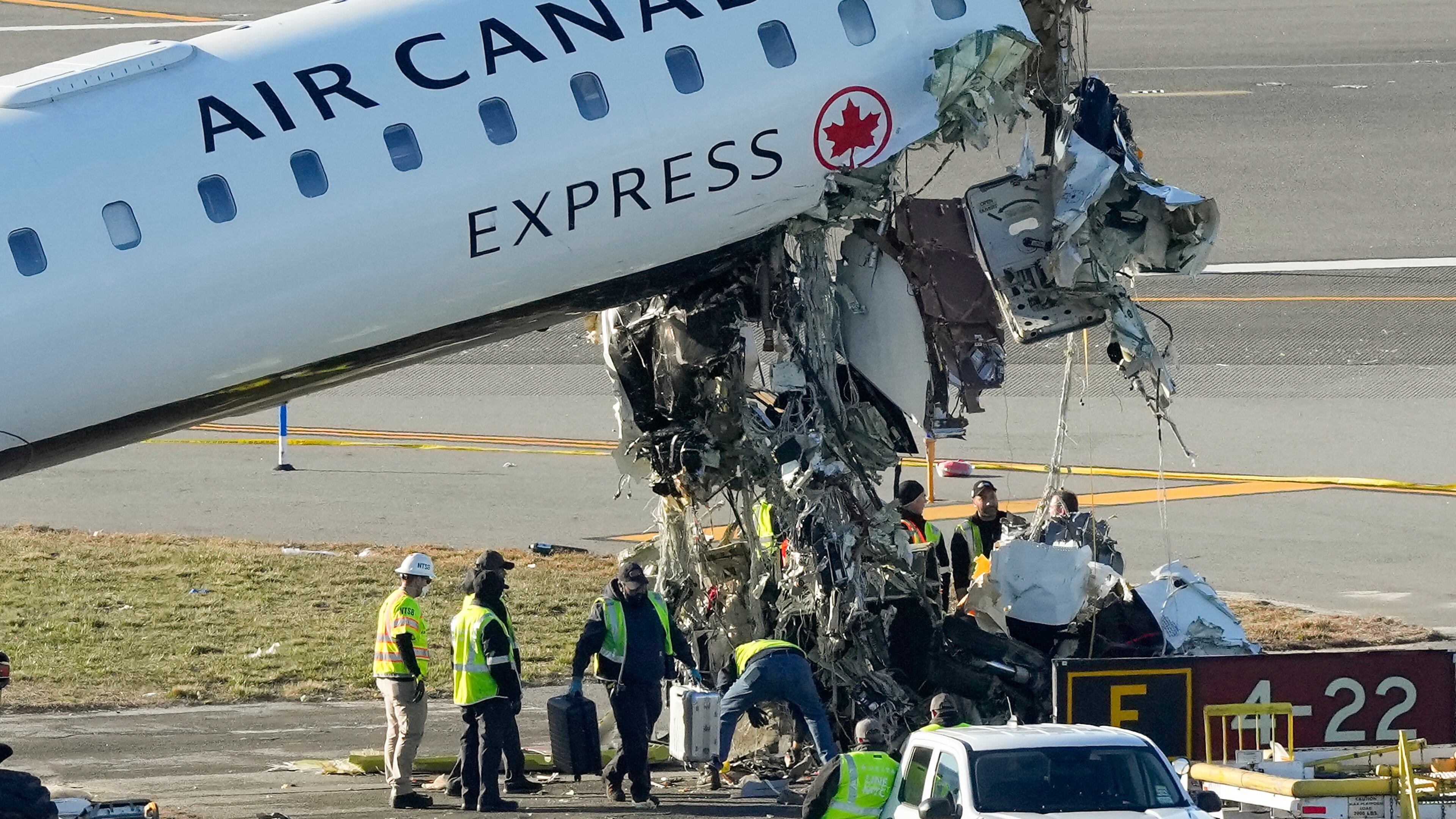NTSB officials and aircraft maintenance workers pick through debris and remove luggage as they inspect the wreckage of an Air Canada Express jet, Tuesday, March 24, 2026, just off the runway where it had collided with a Port Authority fire truck Sunday night at LaGuardia Airport in New York. (AP Photo/Yuki Iwamura)